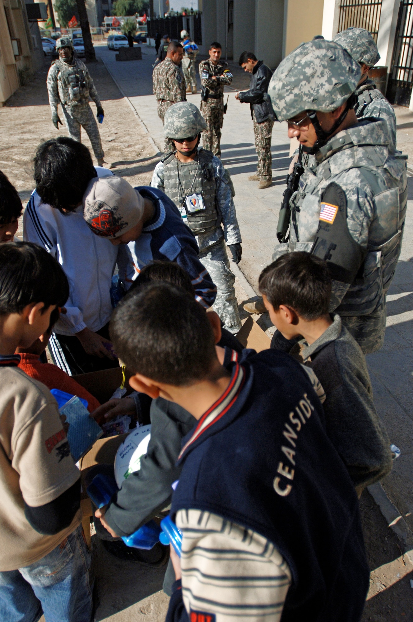 Capt. Ben Washburn hands out toys, school supplies and clothes while on foot-patrol in an apartment complex Jan. 10 in the International Zone of Baghdad, Iraq. The items were gathered by a group of volunteer servicemembers at Joint Base Balad, Iraq, called the Kids of Iraq. The items come from donators in the United States. Captain Washburn is the 732nd Expeditionary Security Forces Squadron Det. 4 operations officer. He is deployed from Vogelway, Germany, and is a native of Colorado Springs, Colo. (U.S. Air Force photo/Tech. Sgt. Craig Lifton) 
