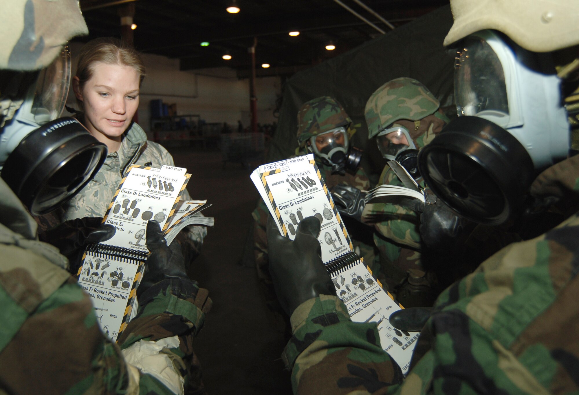MCCONNELL AIR FORCE BASE, Kan. -- Senior Airman Elyce McConnell, 22nd Civil Engineer Squadron, asks Team McConnell Airmen questions as they reference their Airman’s Manuals for the unexploded ordnance that was discovered during a simulated post-attack reconnaissance sweep, Jan. 16. The Mission Oriented Protective Posture transitioning point area overviewed pre- and post-attack actions, contamination avoidance and the M8 chemical agent detection papers. (Photo by Airman 1st Class Maria Ruiz)
