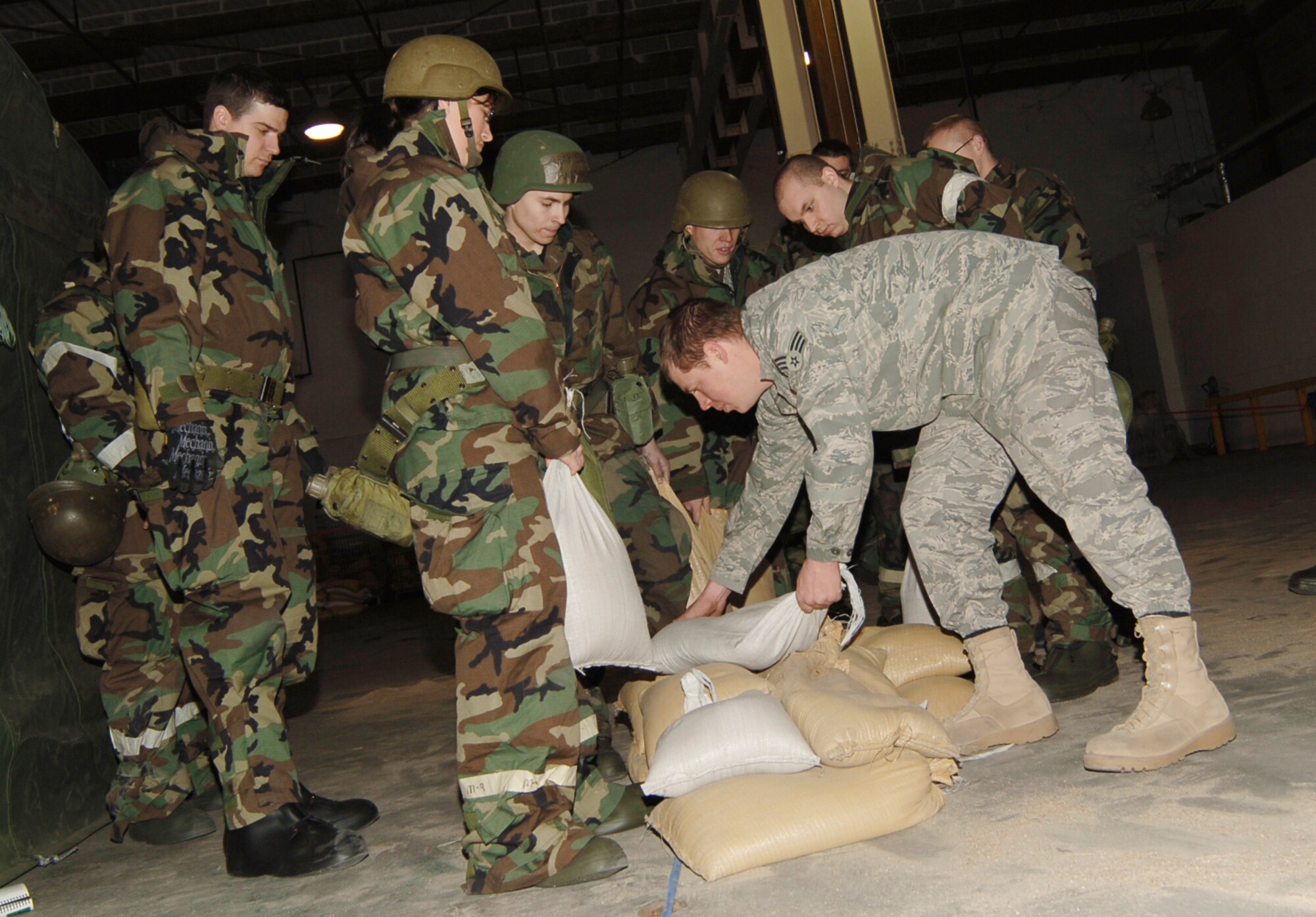 MCCONNELL AIR FORCE BASE, Kan. -- Senior Airman John Durden, 22nd Civil Engineer Squadron, instructs a group of Airmen on how to create an L-shaped corner for a sandbag wall at the hardening/dispersal area, Jan. 16. Airman Durden also reviewed blackout methods, dispersal sites and expedient hardening.   (Photo by Airman 1st Class Maria Ruiz)