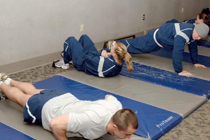 Left to right: Thomas Buena, Lauren Wilson and Colt Brock kick off the 100 Days of Push-ups and Sit-ups Commander's Fitness Challenge during their morning physical training session at the base fitness center Jan. 20. The challenge is a base-wide event for teams of 10 to complete 100,000 push-ups and sit-ups in 100 days. Buena, Wilson and Brock are assigned to the 437th Contracting Squadron. (U.S. Air Force photo/Staff Sgt. Marie Cassetty)