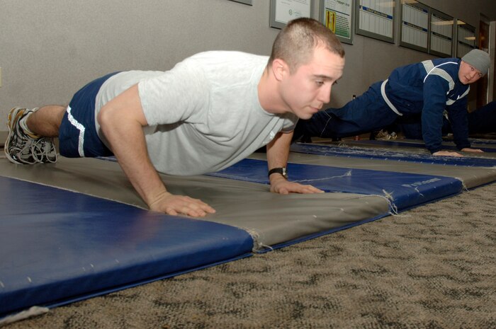 Thomas Buena and Colt Brock kick off the 100 Days of Push-ups and Sit-ups Commander's Fitness Challenge during their morning physical training session at the base fitness center Jan. 20. The challenge is a base-wide event for teams of 10 to complete 100,000 push-ups and sit-ups in 100 days. Buena and Brock are assigned to the 437th Contracting Squadron. (U.S. Air Force photo/Staff Sgt. Marie Cassetty) 
