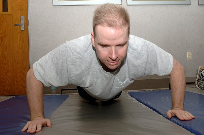 Randy Culbreth kicks off the 100 Days of Push-ups and Sit-ups Commander's Fitness Challenge during his morning physical training session at the base fitness center Jan. 20. The challenge is a base-wide event for teams of 10 to complete 100,000 push-ups and sit-ups in 100 days. Culbreth is the commander of the 437th Contracting Squadron. (U.S. Air Force photo/Staff Sgt. Marie Cassetty)