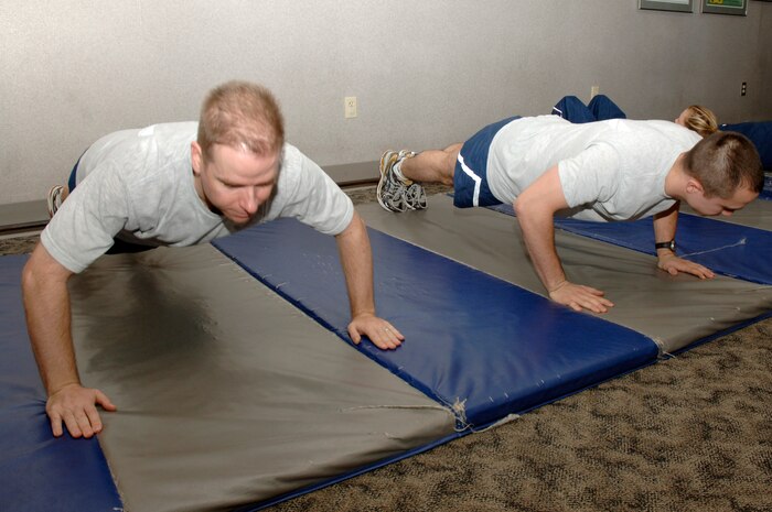Randy Culbreth and Thomas Buena kick off the 100 Days of Push-ups and Sit-ups Commander's Fitness Challenge during their morning physical training session at the base fitness center Jan. 20. The challenge is a base-wide event for teams of 10 to complete 100,000 push-ups and sit-ups in 100 days. Culbreth is the commander of the 437th Contracting Squadron and Buena is assigned to the 437th Contracting Squadron. (U.S. Air Force photo/Staff Sgt. Marie Cassetty)