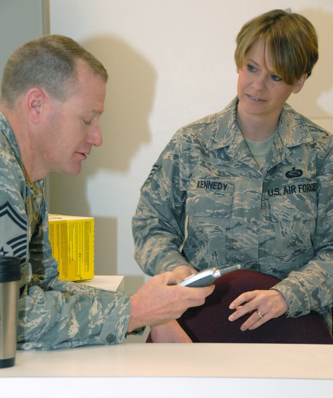 Tech. Sgt. Shannon Kennedy, right, watches her husband, Senior Master Sgt. Rodney Kennedy, call the crew of a C-130 waiting to take reservists from the 442nd Fighter Wing to observe an operational readiness inspection in South Carolina in December.  As the plans and integration superintendent for the 442nd Logistics Readiness Squadron, Rodney organizes the logistics to get reservists to their assigned places.  Shannon, the personnel readiness chief for the 442nd Mission Support Flight, manages the manning requirements to fill deployment assignments.  The husband and wife team are cruccial to deploying reservists from the wing, which is based at Whiteman Air Force Base, Mo.  (U.S. Air Force photo/Maj. David Kurle)