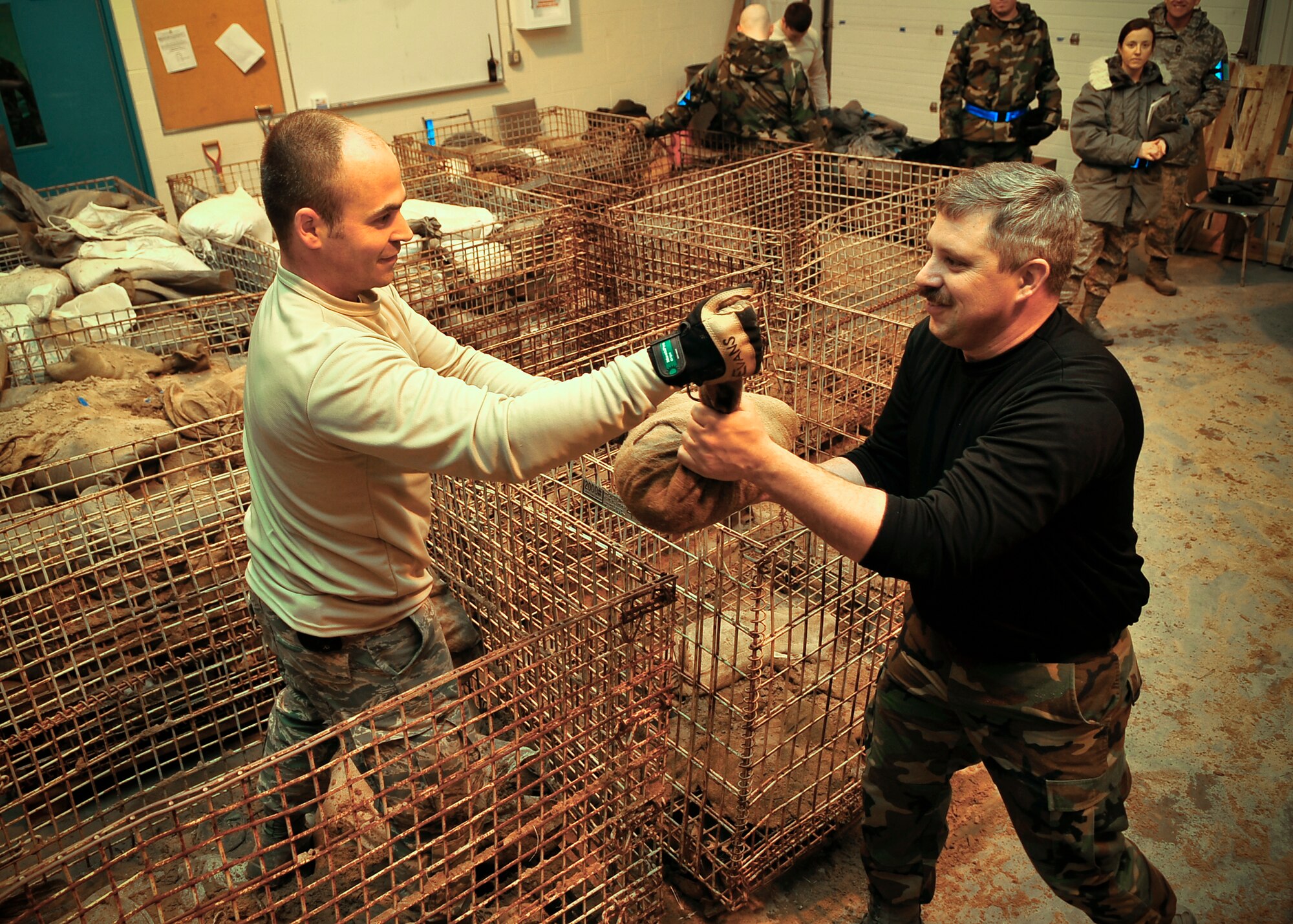 ALPENA, Mich. – Staff Sgt. Chad Evans, 92nd Civil Engineer Squadron structural craftsman, passes a sandbag to Master Sgt. Lajeunesse James, 92nd CES electrical systems craftsman, at a training base in Alpena, Mich., Jan. 12. The sandbags were used to build a semi-hardened structure, which provides equipment protection. The Airmen are required to know how to build such a structure for the upcoming March Operational Readiness Inspection. (U.S. Air Force photo / Senior Airman Joshua Chapman)

