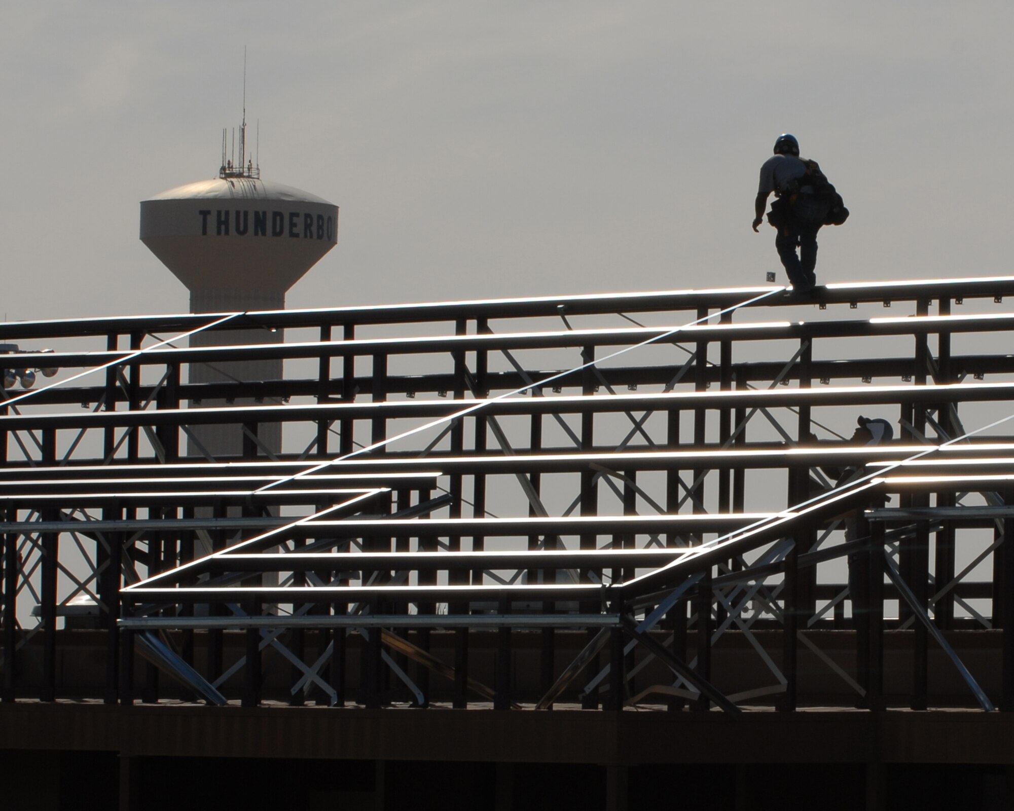 Raul Corona, Alert Roof Systems roofer, contractors of Cram Roofing, catches a panel clip from fellow co-worker Humberto Tadeo on the roof tops of dorm building 637 recently.  (US Air Force photo/Airman 1st Class Ronifel Yasay)