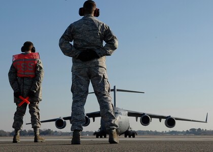Tech. Sgt. Cameron Leslie and Airman Basic Benjamin Oehlke wait to marshal a C-17 for departure on Charleston AFB Jan. 21. For fiscal year 2008, five instructors from the training detachment taught a total of 5,678 hours, graduating 52 new C-17 crew chiefs. Sergeant Leslie is an instructor and Airman Oehlke is in training at the 373rd Training Squadron Detachment 5. (U.S. Air Force photo/Senior Airman Katie Gieratz)
