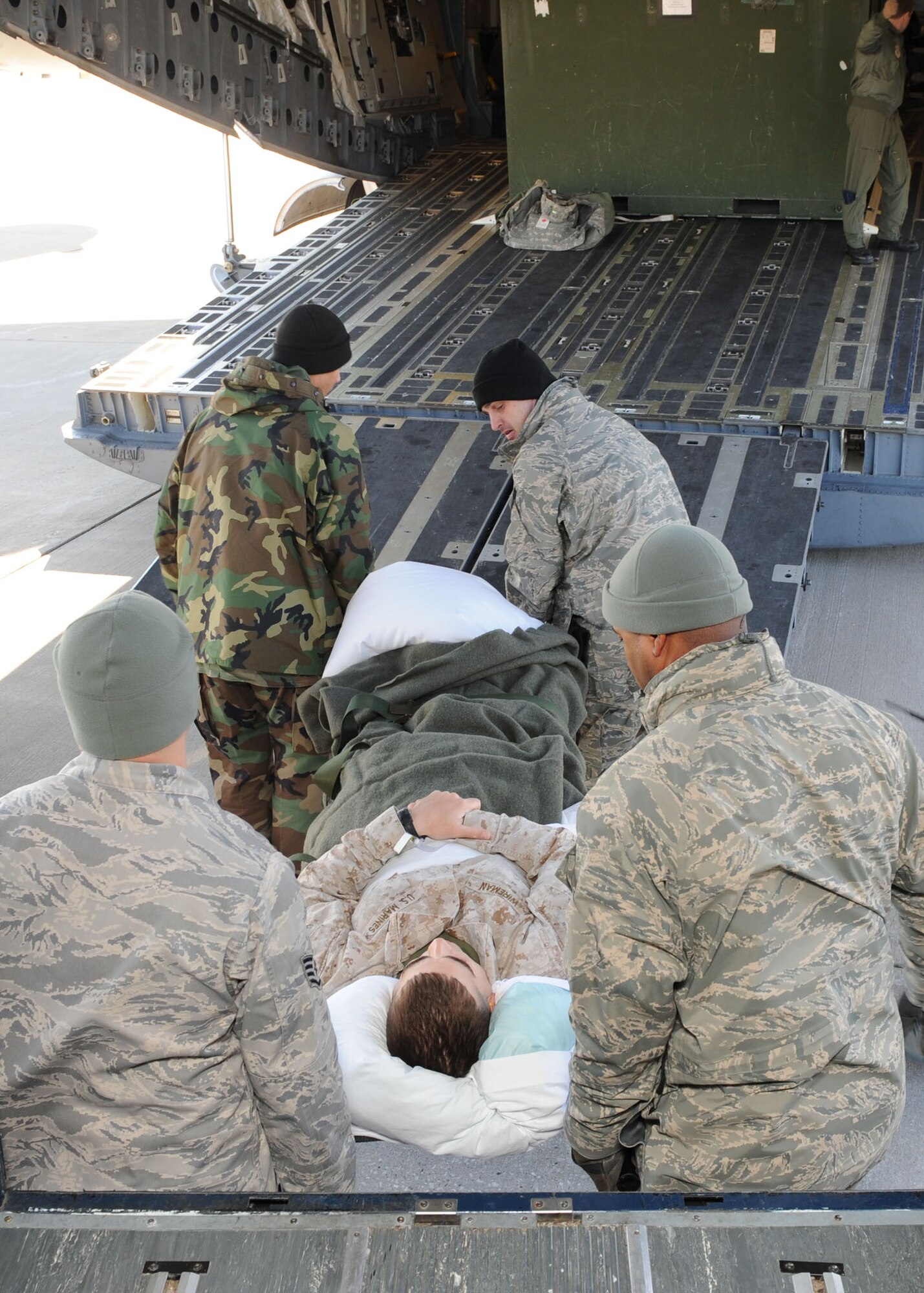 SCOTT AIR FORCE BASE, Ill. -- Members of the 375th Medical Group’s Aeromedical Staging Flight and volunteers from Scott transport a litter patient from a bus to the aircraft that will take him to the next stop on his journey home from overseas. The ASF reached out to Scott looking for volunteers following an increased workload because all missions in and out of Andrews AFB were re-routed to Scott due to the Presidential Inauguration Tuesday. (U.S. Air Force photo/Senior Airman Jonathan Lovelady) 