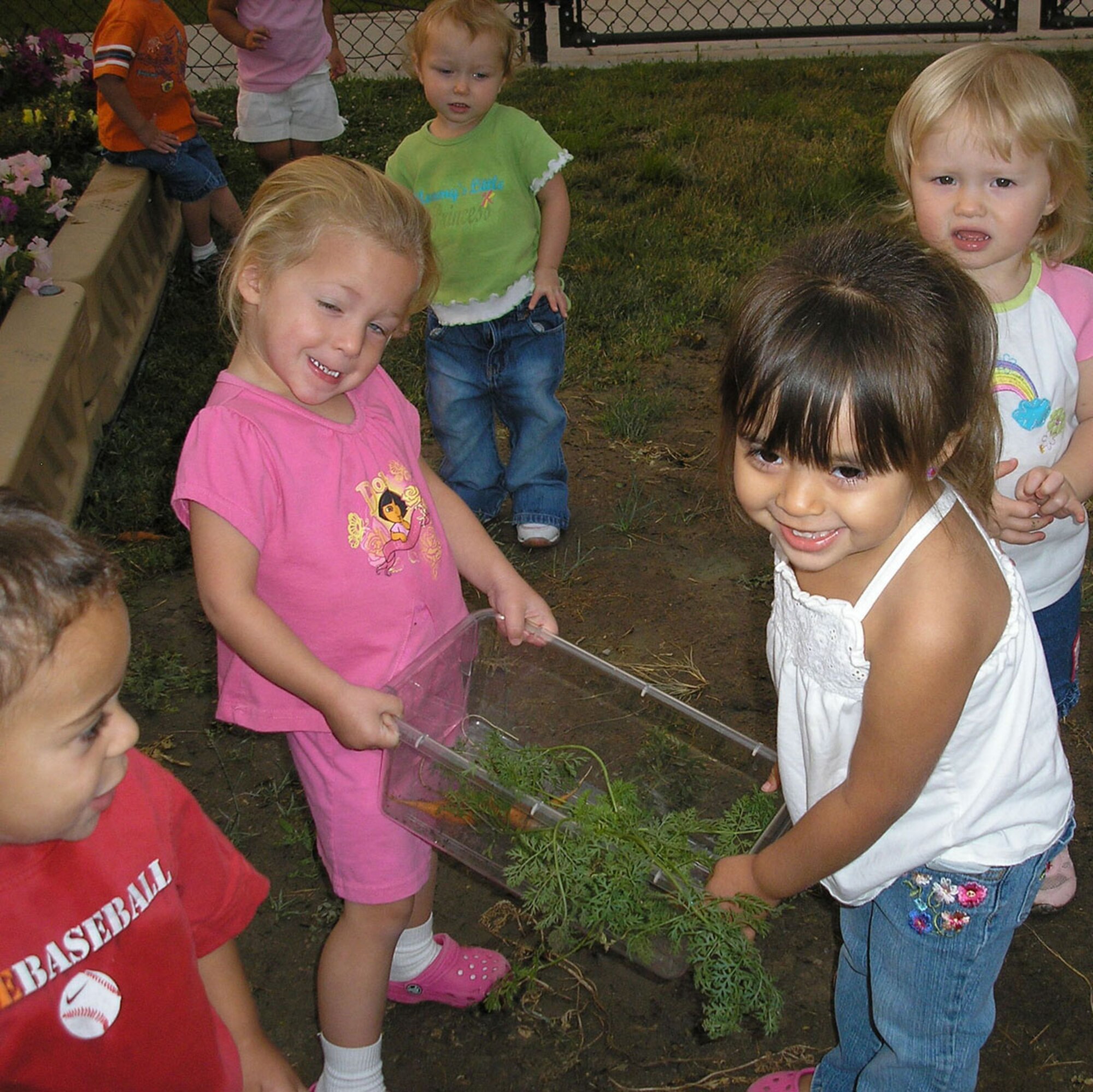 Toddlers registered for care at the Child Development Center pick carrots from the community garden last summer. (Courtesy photo)     