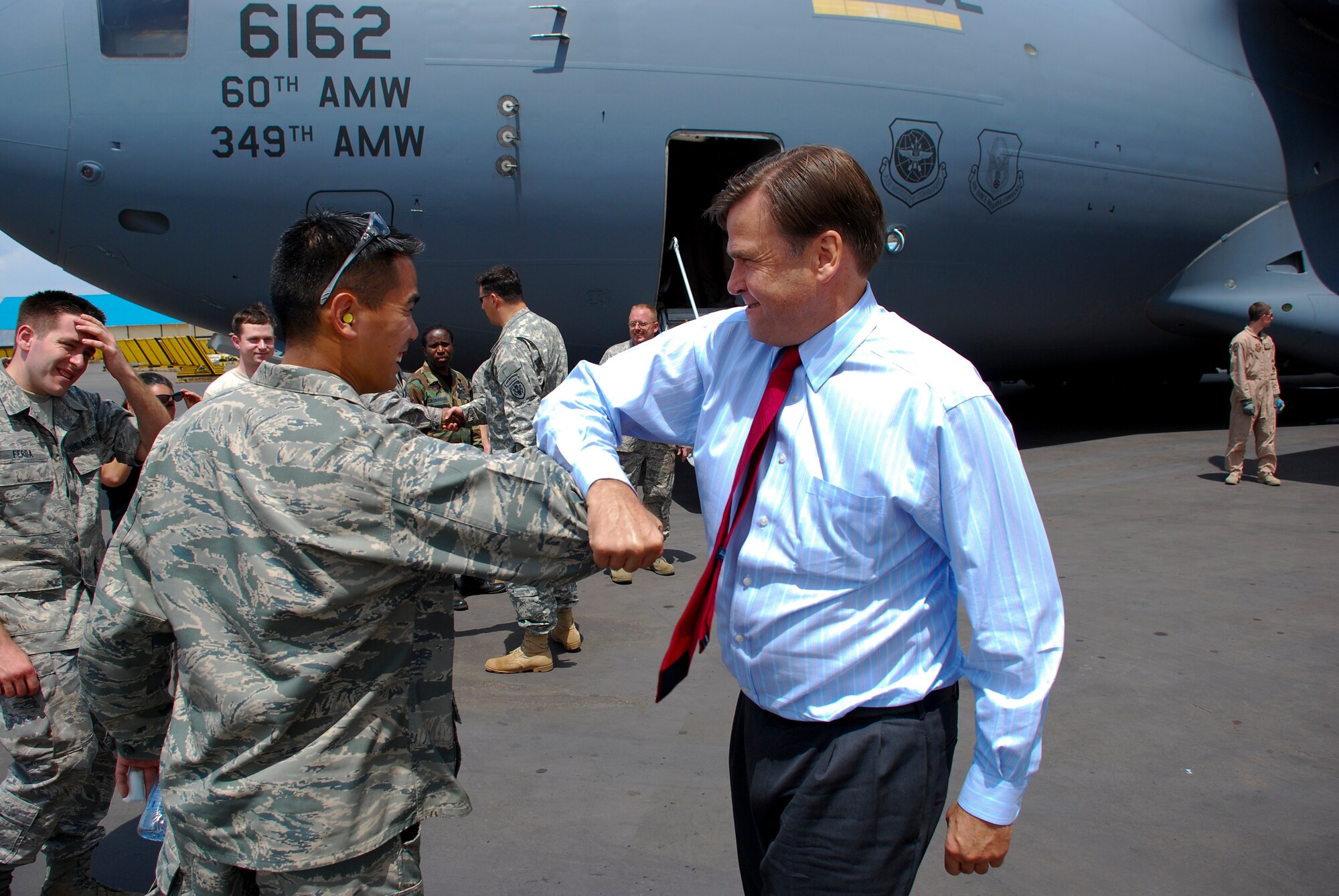 KIGALI, Rwanda -- W. Stuart Symington IV,  U.S. Ambassador to Rwanda, bumps elbows with Air Force Maj. Sang Kim, 722nd Expeditionary Airbase Squadron commander, after loading the last of the Rwandan peacekeeping heavy equipment to be airlifted to Darfur Jan. 16. The operation provided logistical assistance to the United Nations-African Union peacekeepers in the Darfur region of Sudan. This was the first major air operation for Seventeenth Air Force as the air component for U.S. Africa Command. 
Seventeenth, also known as U.S. Air Forces Africa, declared initial operational capability Oct. 1, 2008. The recently-activated numbered air force planned and coordinated aircraft, troops and resources for the operation. 
Airmen, via two C-17 Globemaster III aircraft, moved more than 136 tons of oversized vehicles and special equipment from Kigali to Darfur. Ambassador Symington is the grandson of W. Stuart Symington II, the first Secretary of the Air Force. (Photo by Staff Sergeant Samuel Bendet, U.S. Africa Command)