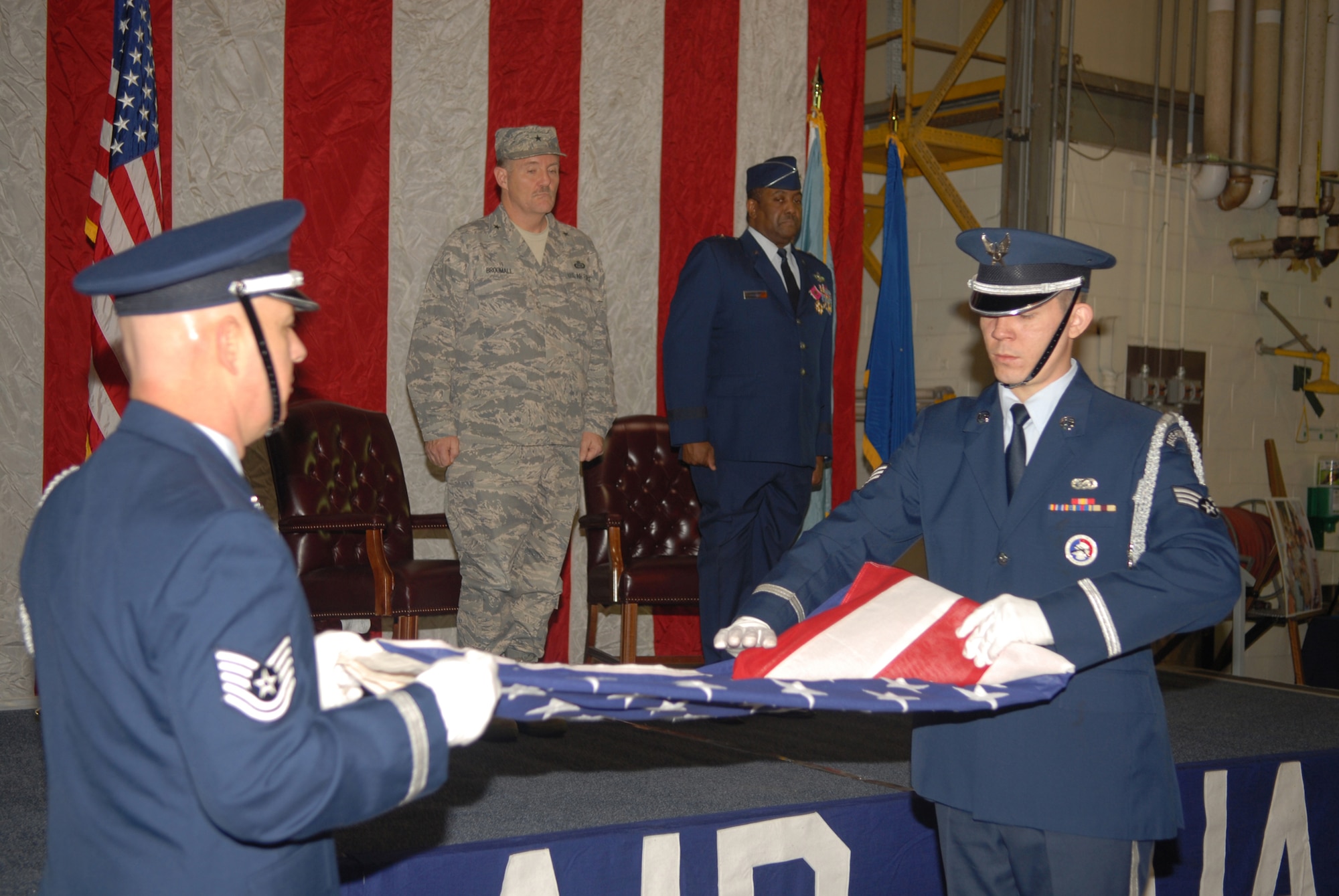 Brig. Gen. Hugh Broomall, Deputy Adjutant General for Air, Delaware National Guard, and Brig. Gen. Ernest Talbert, vice-commander, Delaware Air National Guard, watch from the stage as 166th Airlift Wing Honor Guard members Tech. Sgt. Bill Austin and Senior Airman Joseph O'Leary fold the personal American flag of Gen. Talbert before retiring it during Gen. Talbert's retirement ceremony in New Castle, Del. on Jan. 11, 2009. Gen. Talbert, a rated command pilot with more than 6,500 flight hours, flew C-130 aircraft missions in Operation Desert Storm and was the 166th Airlift Wing commander in Operation Iraqi Freedom. During his 36-year career he became the first African-American colonel in the Delaware ANG, and the first and only African-American general in the over 350-year history of the Delaware National Guard. (U.S. Air Force photo/Staff Sgt. Melissa Chatham)