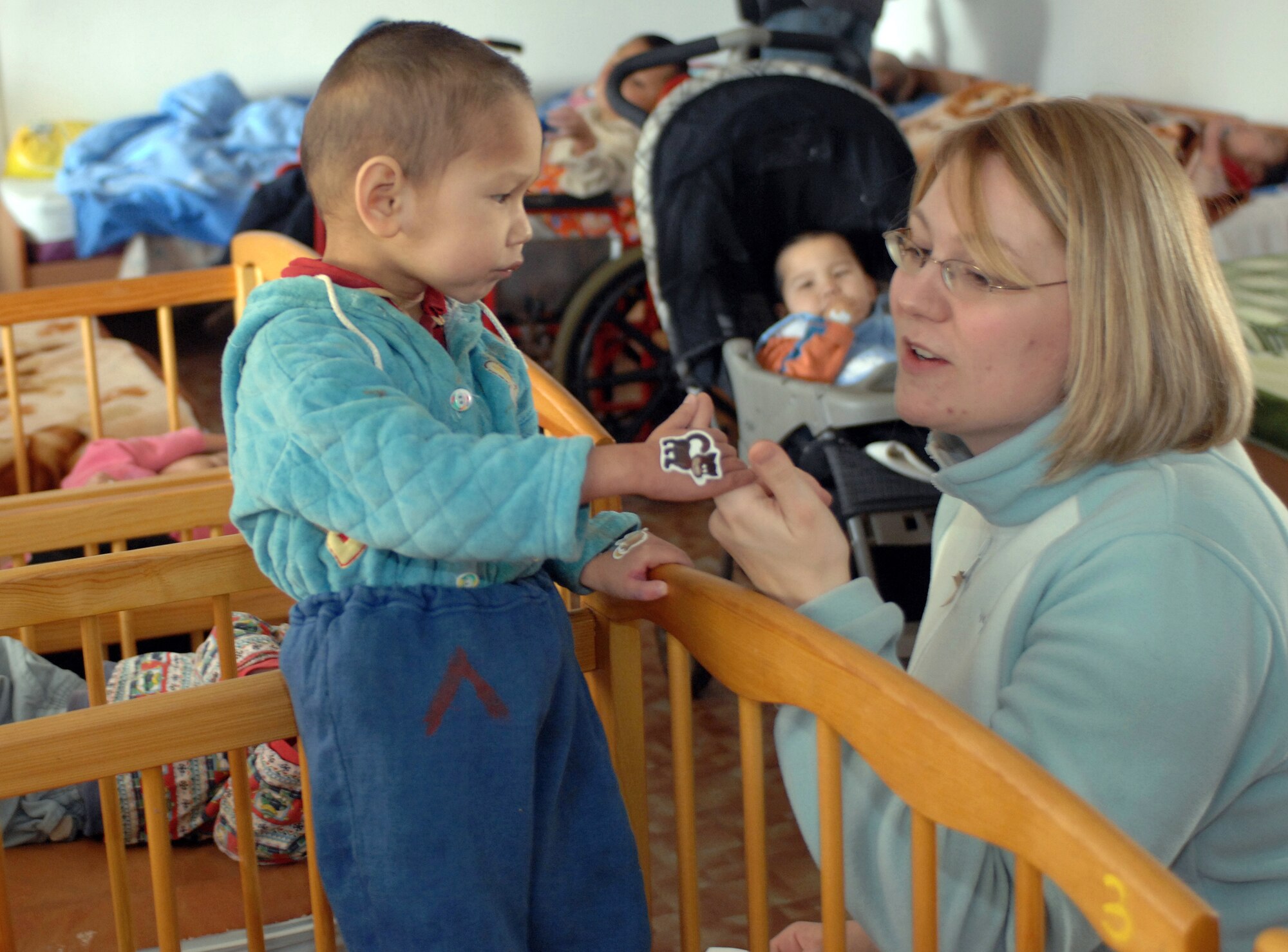 Staff Sgt. Amanda Reggler shares stickers and smiles with a child Jan. 11 at the Belovodosky orphanage north of Bishkek, Kyrgyzstan. Airmen from nearby Manas Air Base visit the orphanage frequently to share friendship and donated toys as well as clothing, blankets, diapers and toiletries. Sergeant Reggler is deployed with the 376th Expeditionary Force Support Squadron. (U.S. Air Force photo/Tech. Sgt. Phyllis Hanson) 
