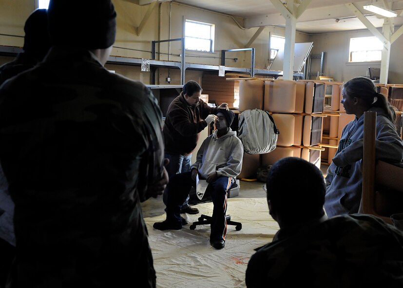 MOODY AIR FORCE BASE Ga., -- Mark Soliz, moulage artist during the All-Hazards Response Training exercise, gives a simulated victim fake injuries while his co-workers watch here Jan 22. The exercise tested the 23rd Medical Group personnel’s ability to quickly respond and treat individuals injured during the simulated scenarios. (U.S. Air Force photo by Senior Airman Brittany Barker)