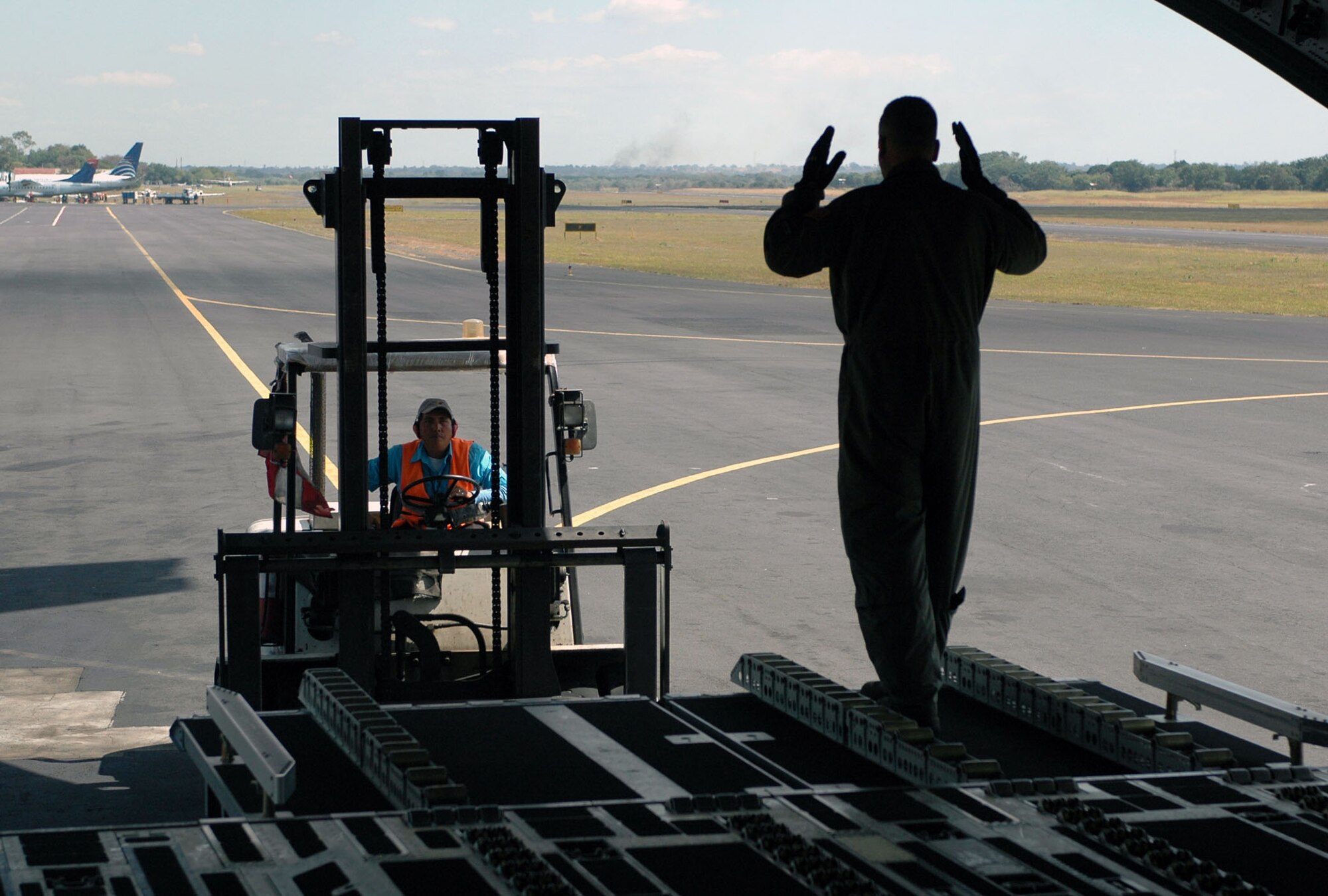 DOVER AIR FORCE BASE, Del. -- Master Sgt. Mike Wright, a loadmaster with the Air Force Reserve's 326th Airlift Squadron, aligns the forklift driver to unload cargo from a C-17 Globemaster at the Managua International Airport, Nicarauga, Jan. 18. Approximately 18,000 pounds of cargo consisting of desks, chairs, file cabinets and books were delivered for use at a Nicaraugan university library. (U.S. Air Force photo/Capt. Marnee A.C. Losurdo)