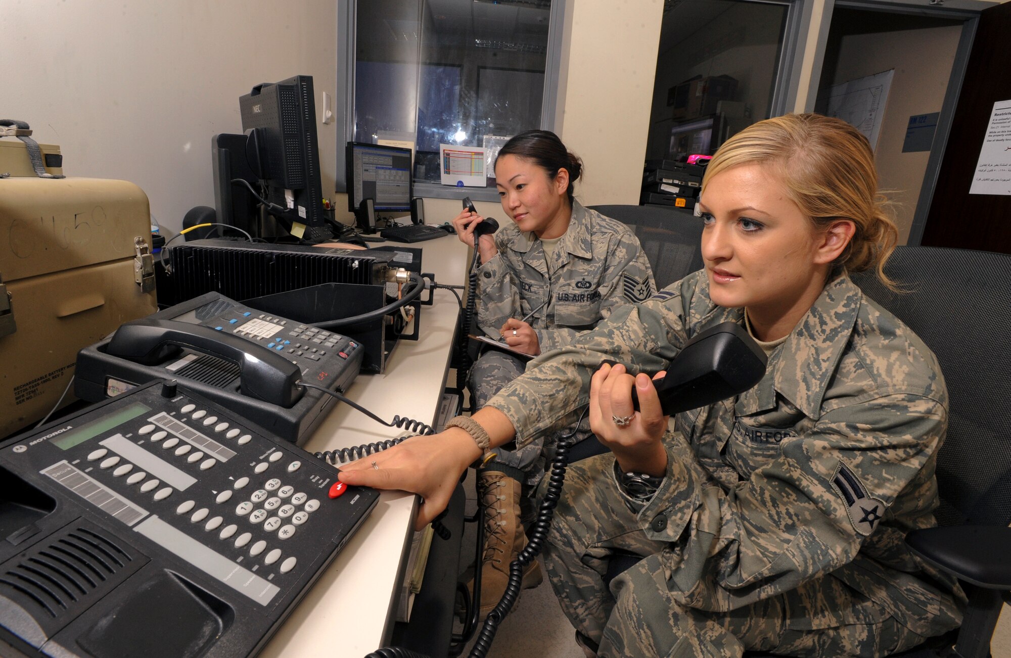 Airman 1st Class Jennifer Holt, the Flight Following Controller for the 379th Air Expeditionary Wing, communicates with wing leadership over the Commander land mobile radio net as Tech. Sgt. Kristi Steck, Non-Commisioned Officer in Charge of Command and Control Operations 379th AEW, takes a call from an inbound C-130 Hercules on an Ultra High Frequency Radio, Jan. 21, 2009, in an undisclosed location in Southwest Asia.  Airman Holt is originally from LaGrange Ill. and is deployed from Luke Air Force Base, Ariz., and Sergeant Steck is from Eugene Ore. and deployed from Ramstein Air Base, Germany in support of Operations Iraqi and Enduring Freedom and Joint Task Force-Horn of Africa.  (U.S. Air Force Photo by Staff Sgt. Joshua Garcia/Released)
