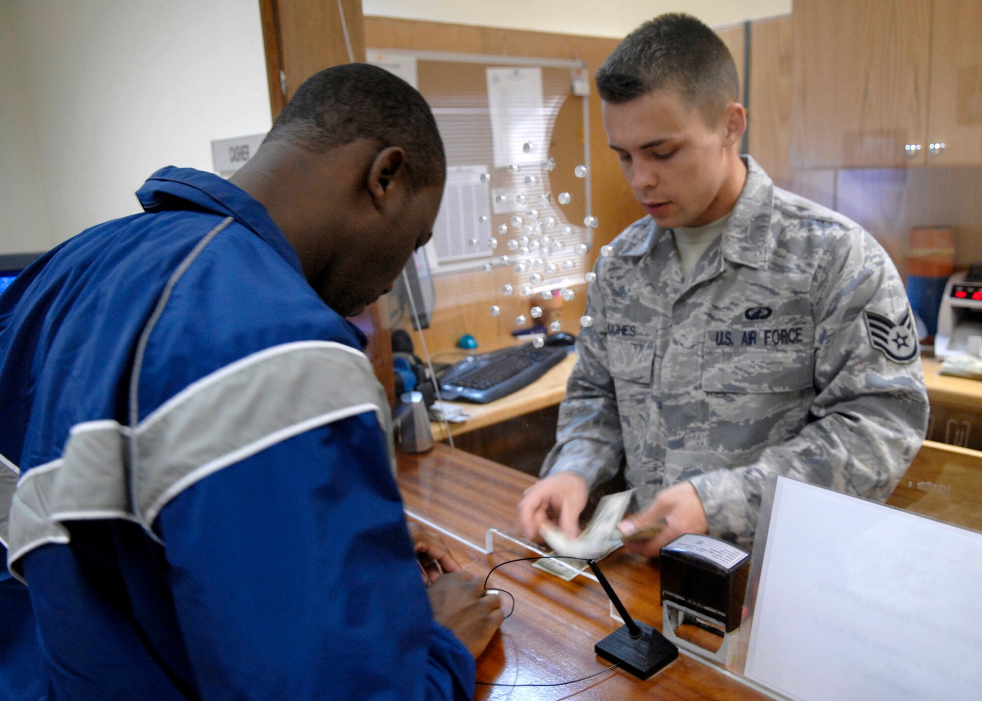 Staff Sergeant Justin Hughes, a 379th Expeditionary Comptrollers Squadron Cashier, counts out cash for a withdrawl for an Airman on base, Jan. 22, 2009, at an undisclosed location in Southwest Asia.  Staff Sgt. Hughes assists Airmen with currency exchanges, cashing checks, and making cash withdrawls.  Staff Sgt. Hughes hails from Anaconda, Mont. and is deployed from Mountain Home Air Force Base, Idaho in support of Operation Iraqi and Enduring Freedom and Joint Task Force- Horn of Africa.  (U.S. Air Force Photo by Airman 1st Class Andrew Satran/Released)