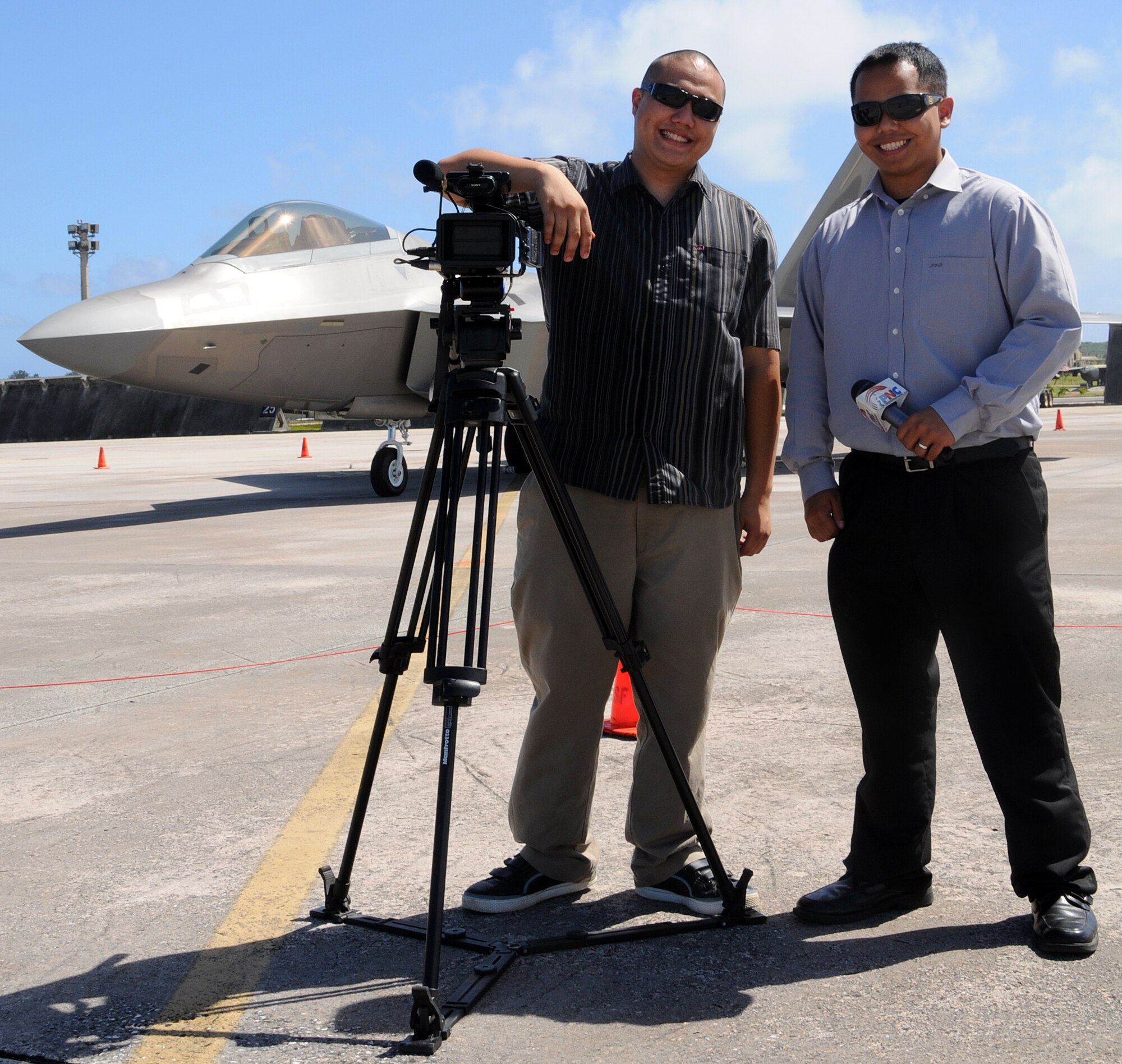 ANDERSEN AIR FORCE BASE, Guam - Cameraman Kevin Milan and news reporter Nick Delgado, from the Pacific News Center, pose here Jan. 23 for a picture in front of an F-22 Raptor deployed from Elmendorf Air Force Base, Alaska. The PNC news crew interviewed Airmen from the 90th Expeditionary Fighter Squadron. (U.S. Air Force photo by Airman 1st Class Courtney Witt)