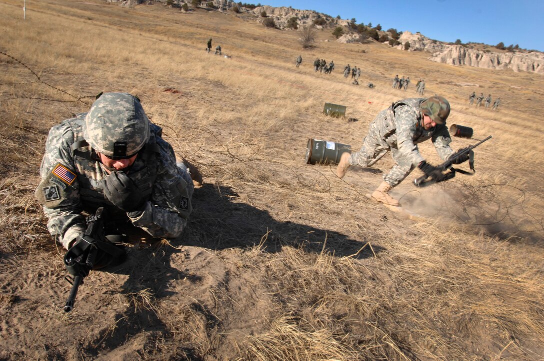 Army Sgt. 1st Class Doug Brenneman breaches a concertina wire strand as Staff Sgt. Mike Benskin provides cover during pre-deployment training at the Wyoming National Guard training site Camp Guernsey, Wyo., Jan. 10, 2009. Both are assigned to the 148th Signal Company out of Laramie, Wyo. 