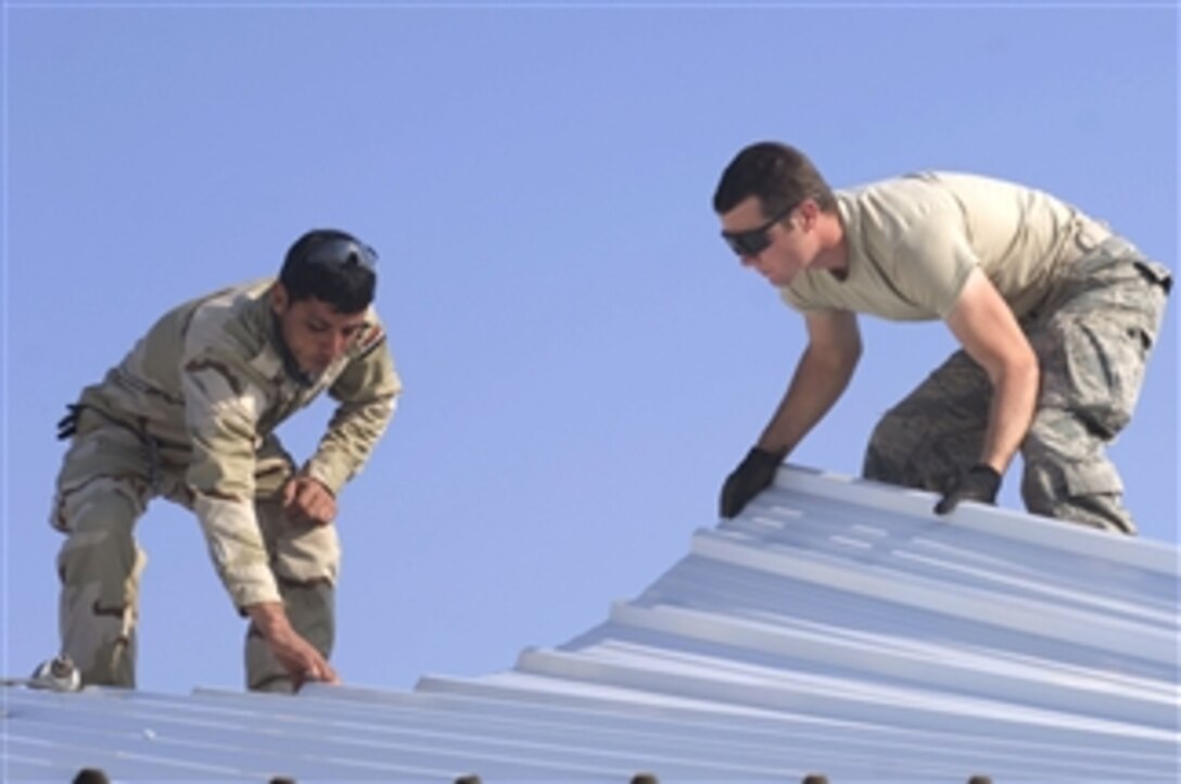 U.S. Air Force Senior Airman James Parritt (right) and an Iraqi soldier attach sheet metal roofing to a newly constructed building at Diyala Media Center Combat Outpost, Iraq, on Jan. 21, 2009.  U.S. airmen attached to 555th Engineer Brigade and Iraqi soldiers from 5th Construction Engineer Battalion are building living quarters for U.S. soldiers at the outpost.  