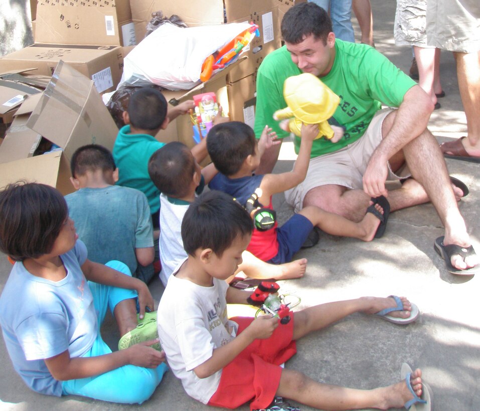 Capt. Zak Blom, a 17th SOS pilot, listens to children at the Duyan ni Maria orphanage in Angeles City, Pampanga in the Philippines Jan. 19 after handing them toys from the donations members of the 353rd Special Operations Group delivered. Members of the 17th Special Operations Squadron, 353rd Operations Support Squadron and Detachment 3 of the 25th Intelligence Squadron stopped by the orphanage and single mothers home with boxes of clothing, shoes, toys, books and school supplies before returning home from an overnight mission supporting U.S. Army forces deployed for Operation Enduring Freedom-Philippines.  (Courtesy Photo)
