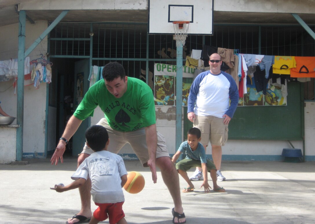 Capt. Zak Blom, a 17th SOS pilot, and Capt. Matt Halladay, a 17th SOS navigator, play basketball with children at the Duyan ni Maria orphanage in Angeles City, Pampanga in the Philippines Jan. 19. Members of the 17th Special Operations Squadron, 353rd Operations Support Squadron and Detachment 3 of the 25th Intelligence Squadron stopped by the orphanage and single mothers home with boxes of clothing, shoes, toys, books and school supplies before returning home from an overnight mission supporting U.S. Army forces deployed for Operation Enduring Freedom-Philippines. (Courtesy Photo)