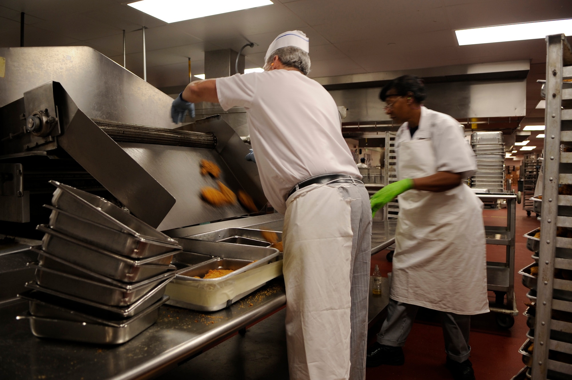 Patrick Burns and Betty Hayes pull chicken from the "monster," or deep fryer, Jan. 23 in preparation for lunch at Mitchell Hall Cadet Dining Facility at the U.S. Air Force Academy in Colorado Springs, Colo. The dining facility feeds approximately 4450 cadets and sits on 1.75 acres. (U.S Air Force photo/Staff Sgt. Desiree N. Palacios)