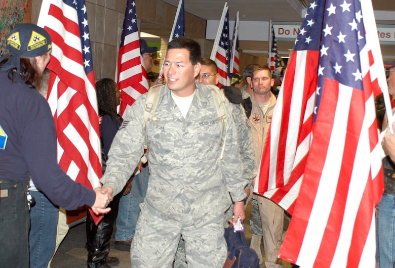 Staff Sgt. David Ruiz shakes hands with a member of the Patriot Riders. Family and friends crowded the baggage claim area at Tucson International Airport to welcome home 28 aircraft maintainers and pilots. The Guardsmen volunteered for tours ranging from 8 months to 30 days in duration. (Air National Guard photo by Capt. Gabe Johnson)