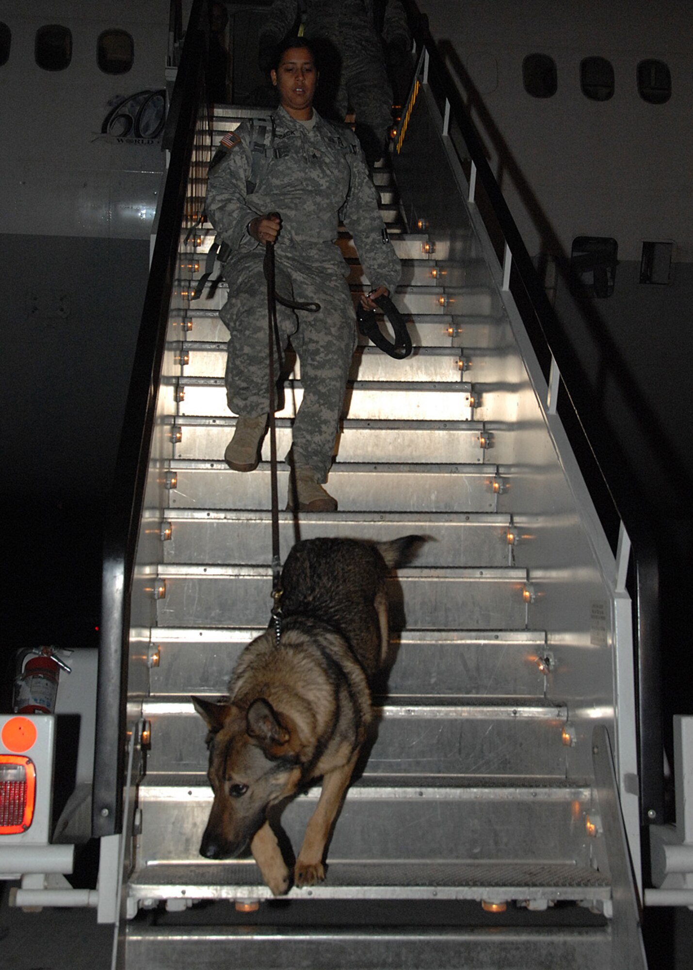 SOUTHWEST ASIA -- Army Sgt. Chantel Razack and Pindo, military working dog team, arrive at an air base in Southwest Asia, to wait for another aircraft to take them to Iraq, Jan. 24. All MWD teams pass through this air base because it has the only MWD Hub, providing them with a place to sleep, devoted veterinary care, weapon storage and assistance with their connecting flight into the fight.  (U.S. Air Force photo/Senior Airman Courtney Richardson)