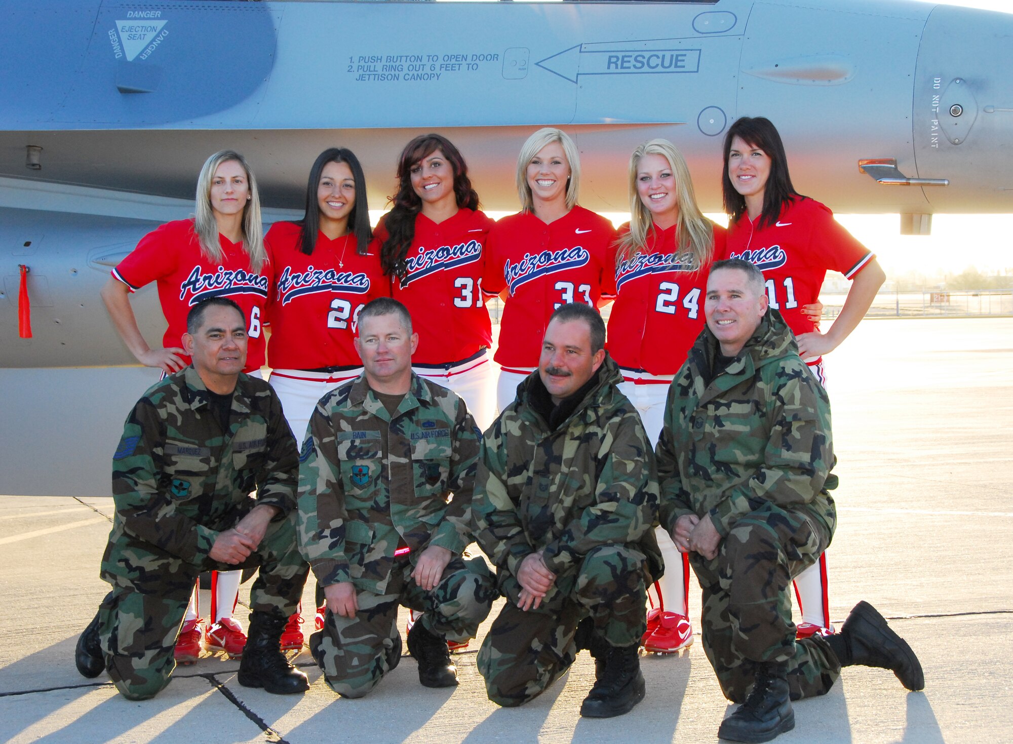 (From left to right) Tech. Sgt. Dave Marquez, Tech. Sgt. Rick Bain, Tech. Sgt. Jeff Maeser and Master Sgt. Jay Good take a souvenir photograph with members of the UofA Softball team in front of an F-16 on the flightline here Jan. 27. The Aircraft maintainers coordinated with UofA photographers to position the aircraft at the right angle for the sunrise photo shoot. (Air National Guard photo by Master Sgt. Dave Neve)