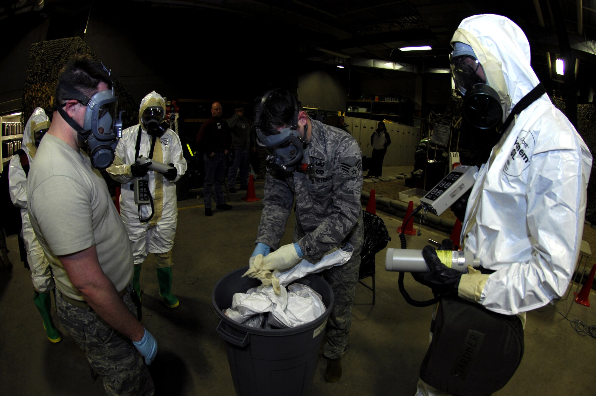MINOT AIR FORCE BASE, N.D. -- Senior Airman James Tucci, 5th Civil Engineer Squadron explosive ordnance device team member, carefully removes his gloves, while his wingmen, Senior Airman Aaron Feil and Airman 1st Class Aaron Gardner, both 5th CES readiness emergency management team members, monitor him during the Prairie Warrior 09-2 wing exercise here Jan. 22. The exercise tested the base's ability to respond to a simulated attack which resulted in a possible chemical spill. (U.S. Air Force photo by Tech. Sgt. Lee A. Osberry Jr.)   