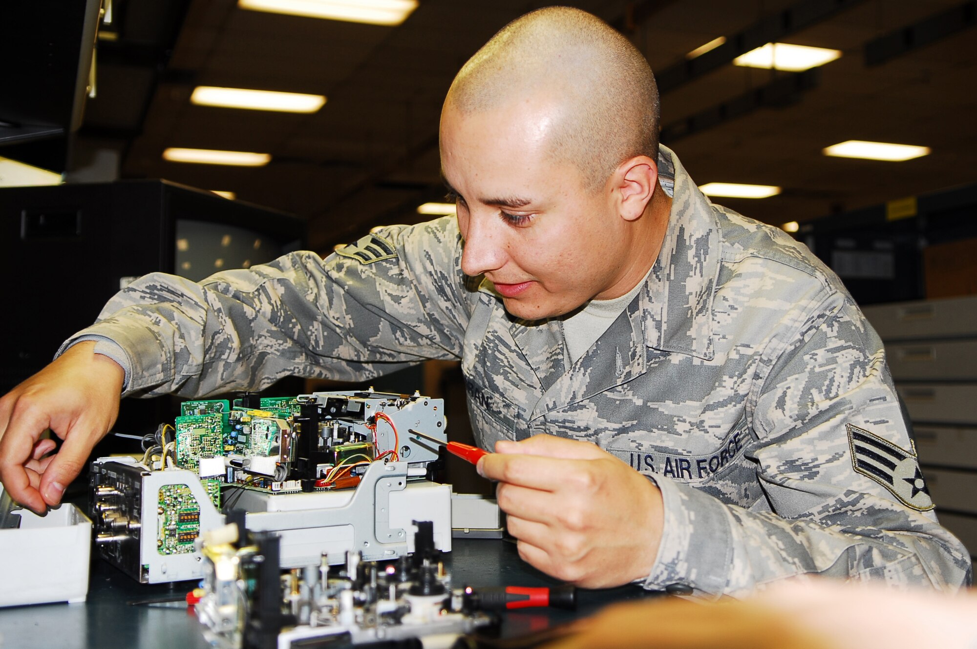 Senior Airman Roger Duran, 56th Component Maintenance Squadron avionics intermediate systems shop team member, reaches for a screw to reassemble an airborne video tape recorder carriage January 26 in the AIS back shop. AIS is the only shop on base equipped to perform maintenance on AVTRs. (Air Force photo by Staff Sgt. Phillip Butterfield)