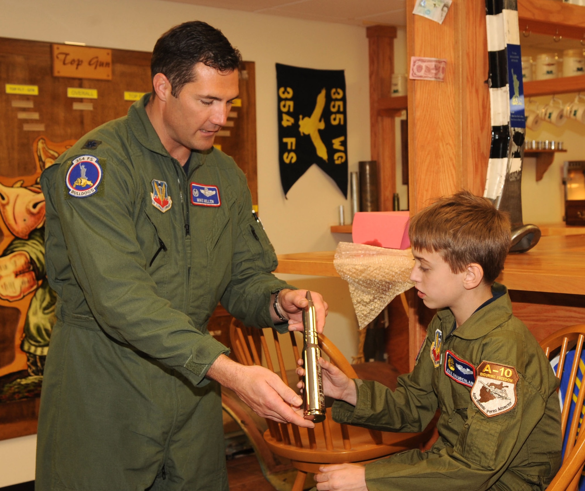 Lt. Col. Michael Millen, 354th Fighter Squadron Commander, presents Kyle Chamberlain, 13, with a chrome 30mm bullet engraved with his name Jan 23. The Pilot For A Day program is designed to help children with disabilities or serious illnesses enjoy a day focused on them and their interest in aviation. (U.S. Air Force photo Airman 1st Class Brittany Dowdle)