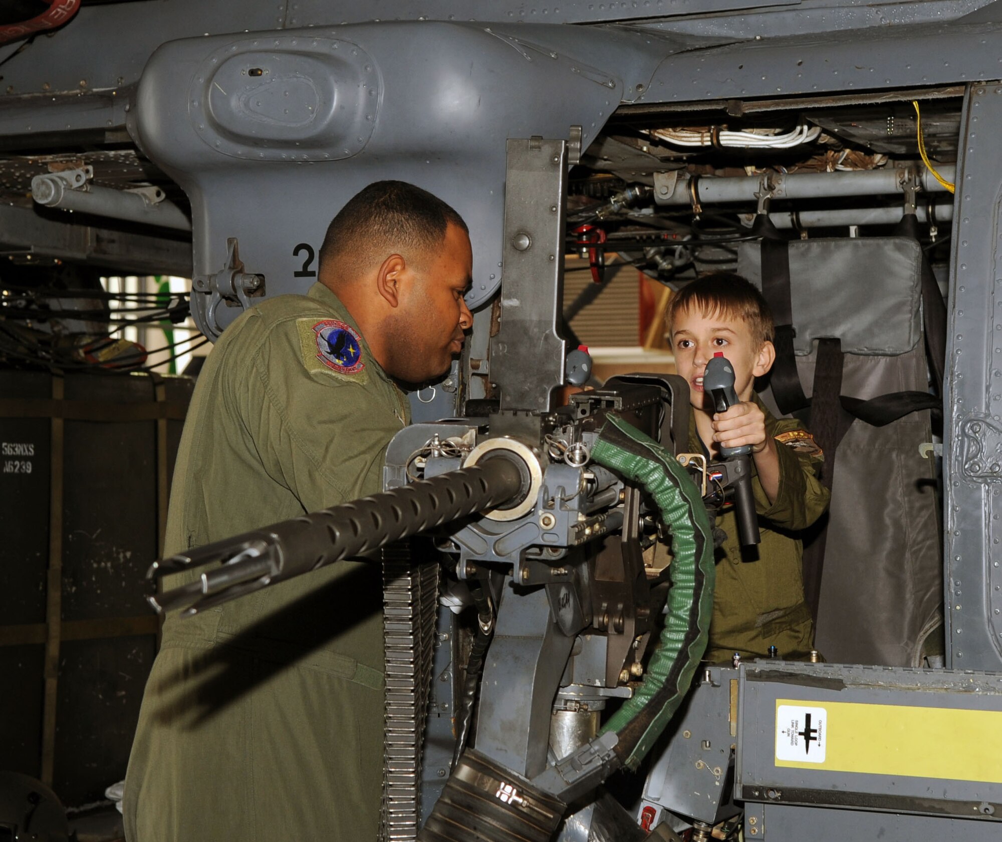 Staff Sgt. Chauncey Padilla, an aerial gunner with the 55th Rescue Squadron, shows 13-year-old Kyle Chamberlain a .50 caliber gun on the side of an HH-60 Pave Hawk during Kyle's visit to D-M Jan. 23. The Pilot For A Day program is designed to help children with disabilities or serious illnesses enjoy a day focused on them and their interest in aviation. (U.S. Air Force photo Airman 1st Class Brittany Dowdle)