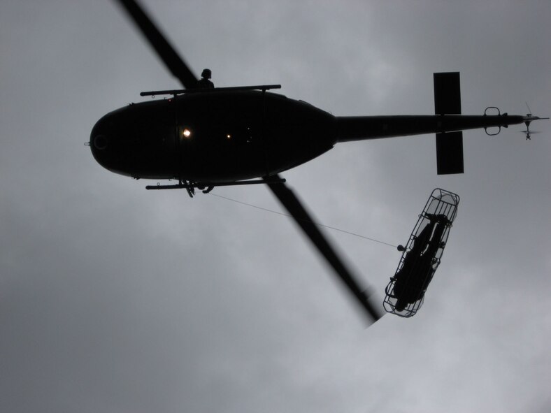 A “stokes litter” carrying an accident victim is hoisted up to a UH-1N Huey helicopter from the 40th Helicopter Squadron.  Once the patient is on board the aircraft, a flight surgeon or flight nurse can perform a life-saving role while en route to a local hospital or care facility for treatment. At Malmstrom, flight surgeons and flight nurses are required to accomplish one day and one night hoist per calendar year for training.  (U.S. Air Force photo/Capt. David Oettel)
