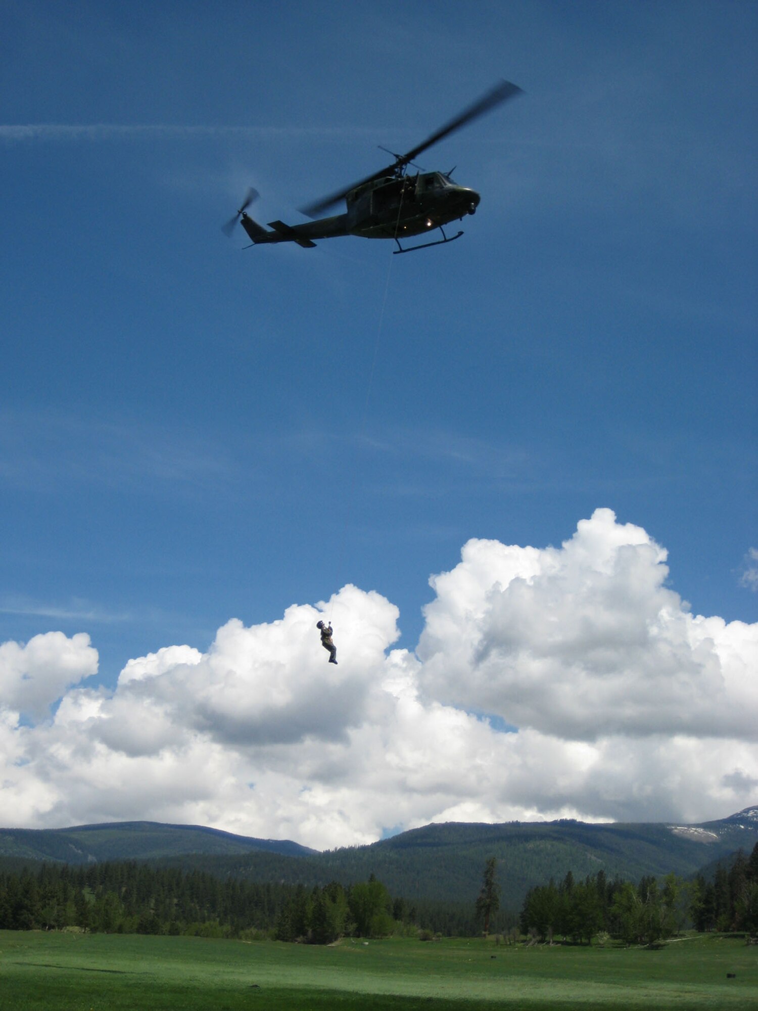 Capt. Mitchell Parrish, 341st Medical Operations Squadron flight surgeon, gets a lift from a UH-1N Huey helicopter from the 40th Helicopter Squadron in a field in rural Montana. Captain Parrish is hoisted up 120 feet sitting on a “force penetrator” while participating in a search and rescue exercise in May 2008. At Malmstrom, flight surgeons and flight nurses are required to accomplish one day and one night hoist per calendar year for training.  (U.S. Air Force photo/Capt. David Oettel)