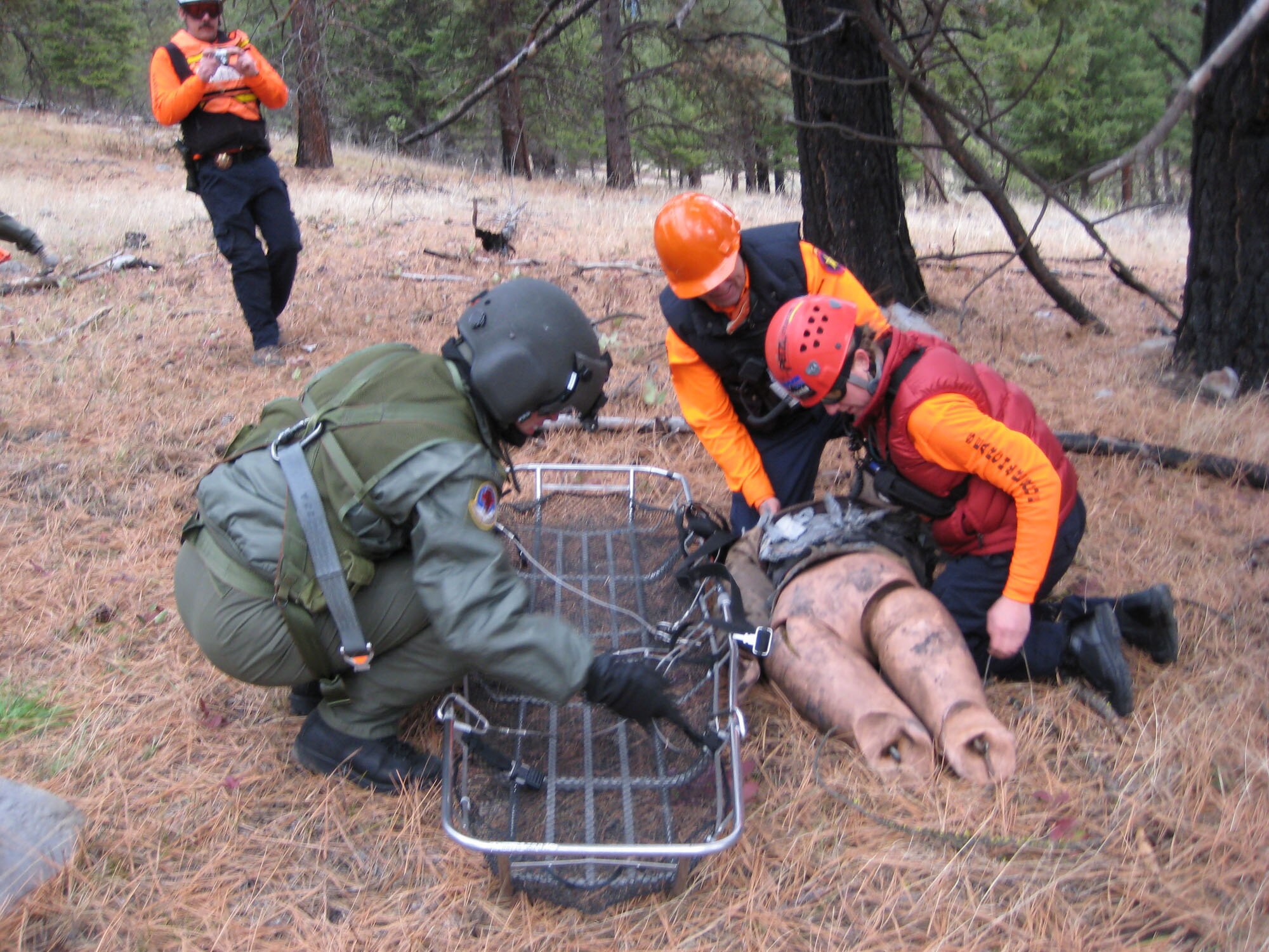 Capt. Mitchell Parrish, 341st Medical Operations Squadron flight surgeon (left), participates in a search and rescue exercise with the Missoula County Search and Rescue team near Missoula, Mont., November 2008. The crews attempt to safely roll a “dummy” victim into a “stokes litter,” which is then hoisted in the air to the helicopter hovering above. At Malmstrom, flight surgeons and flight nurses are required to accomplish one day and one night hoist per calendar year for training. (U.S. Air Force photo/Capt. David Oettel).