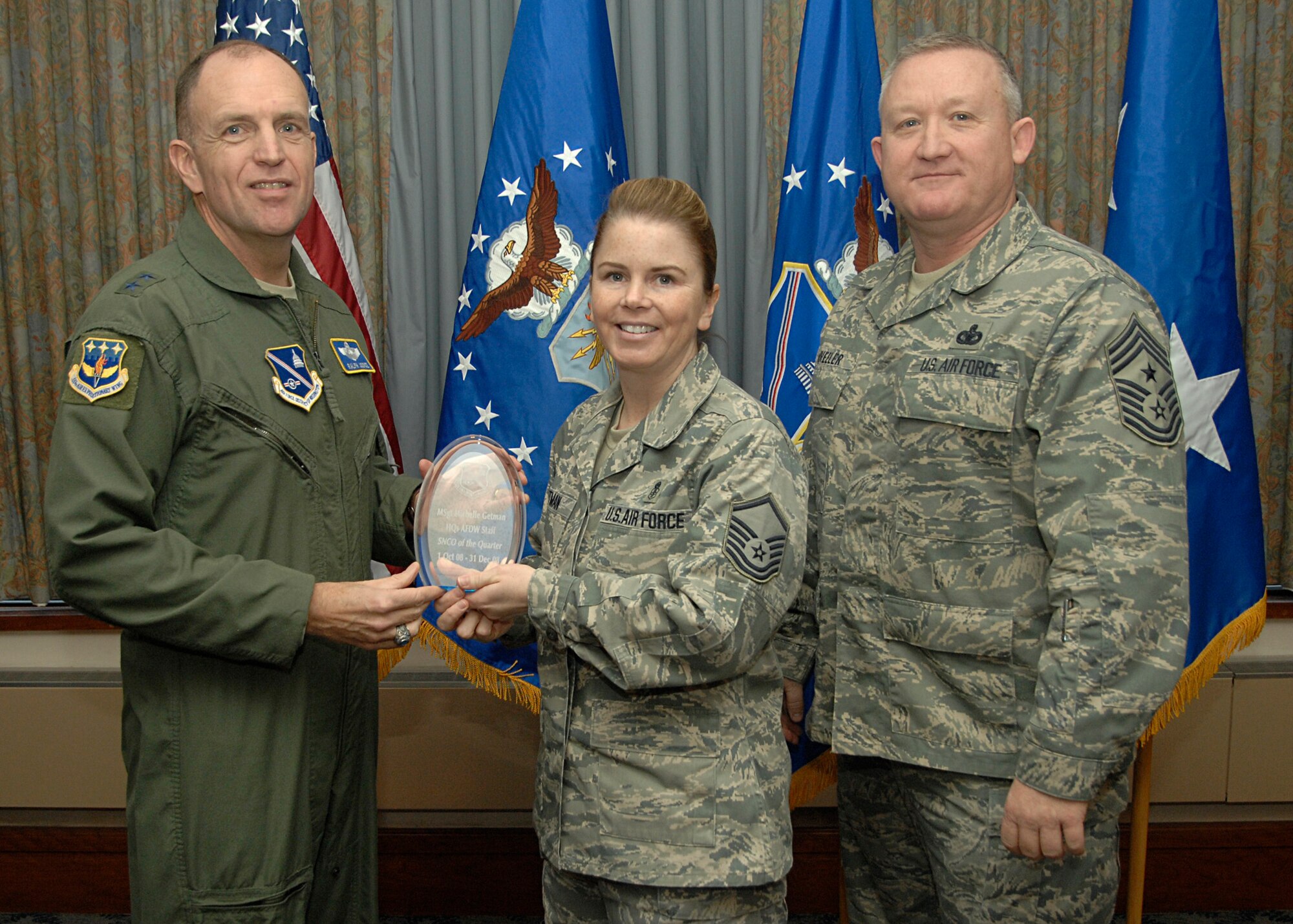 Air Force District of Washington Senior NCO of the Quarter, Master Sgt. Michelle L. Getman, receives her award from AFDW Commander Maj. Gen. Ralph Jodice, and AFDW Command Chief, Chief Master Sgt. Paul Wheeler, during the AFDW 4th Quarter Awards Ceremony, held Jan. 22 at the Andrews Air Force Base club. Sergeant Getman is NCOIC of the Special Missions Division in the AFDW A3/5 directorate. 