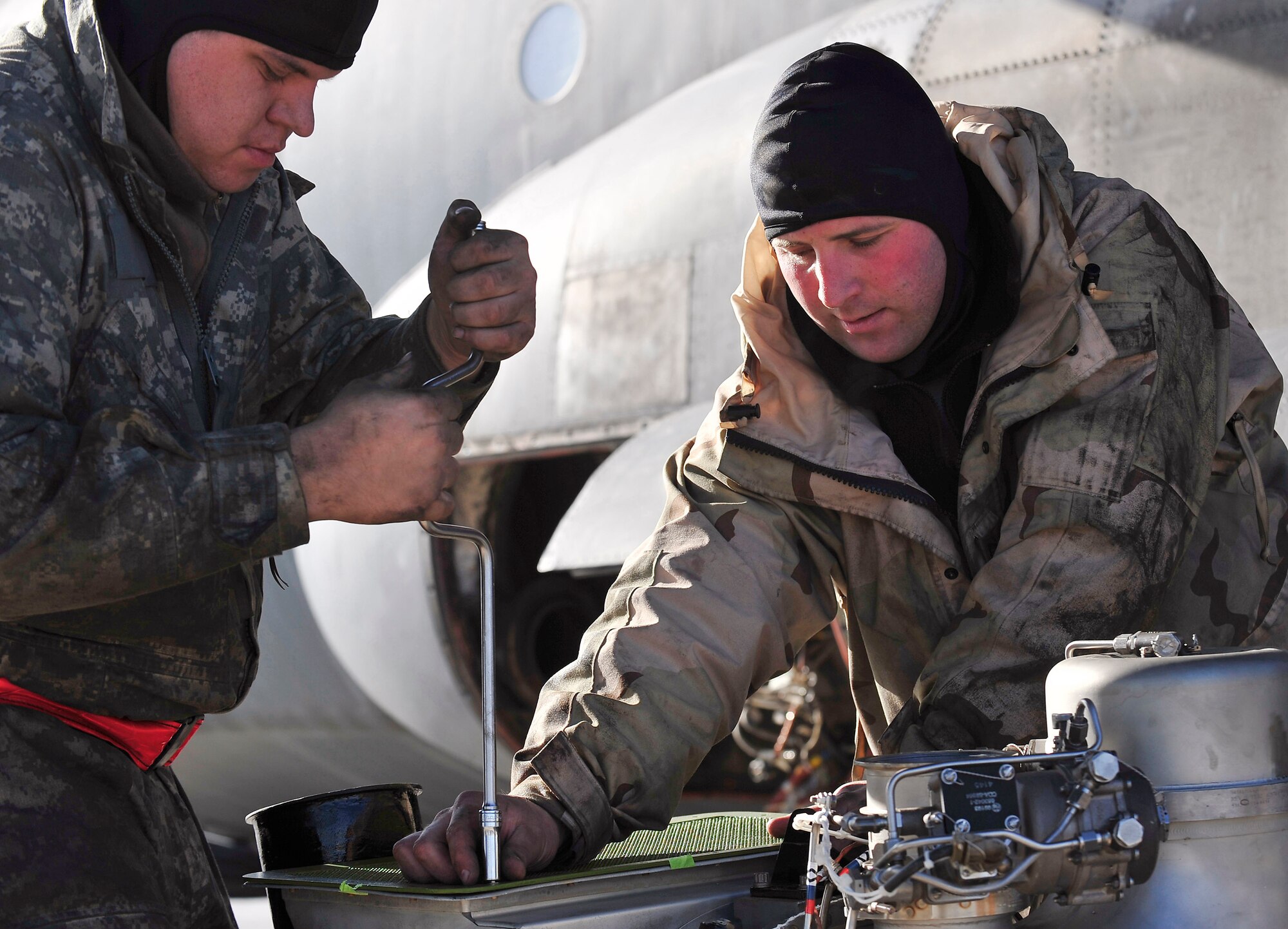 Technical Sgt. Sam Harmon assists Senior Airman Billy Howell in removing an inlet duct protector Jan. 16 at Joint Base Balad, Iraq. This is one of many steps in changing an auxiliary power unit of a C-130 Hercules. Sergeant Harmon and Airman Howell are 777th Expeditionary Aircraft Maintenance Unit jet engine mechanics. They are deployed from Little Rock Air Force Base, Ark. (U.S. Air Force photo/Senior Airman Elizabeth Rissmiller) 
