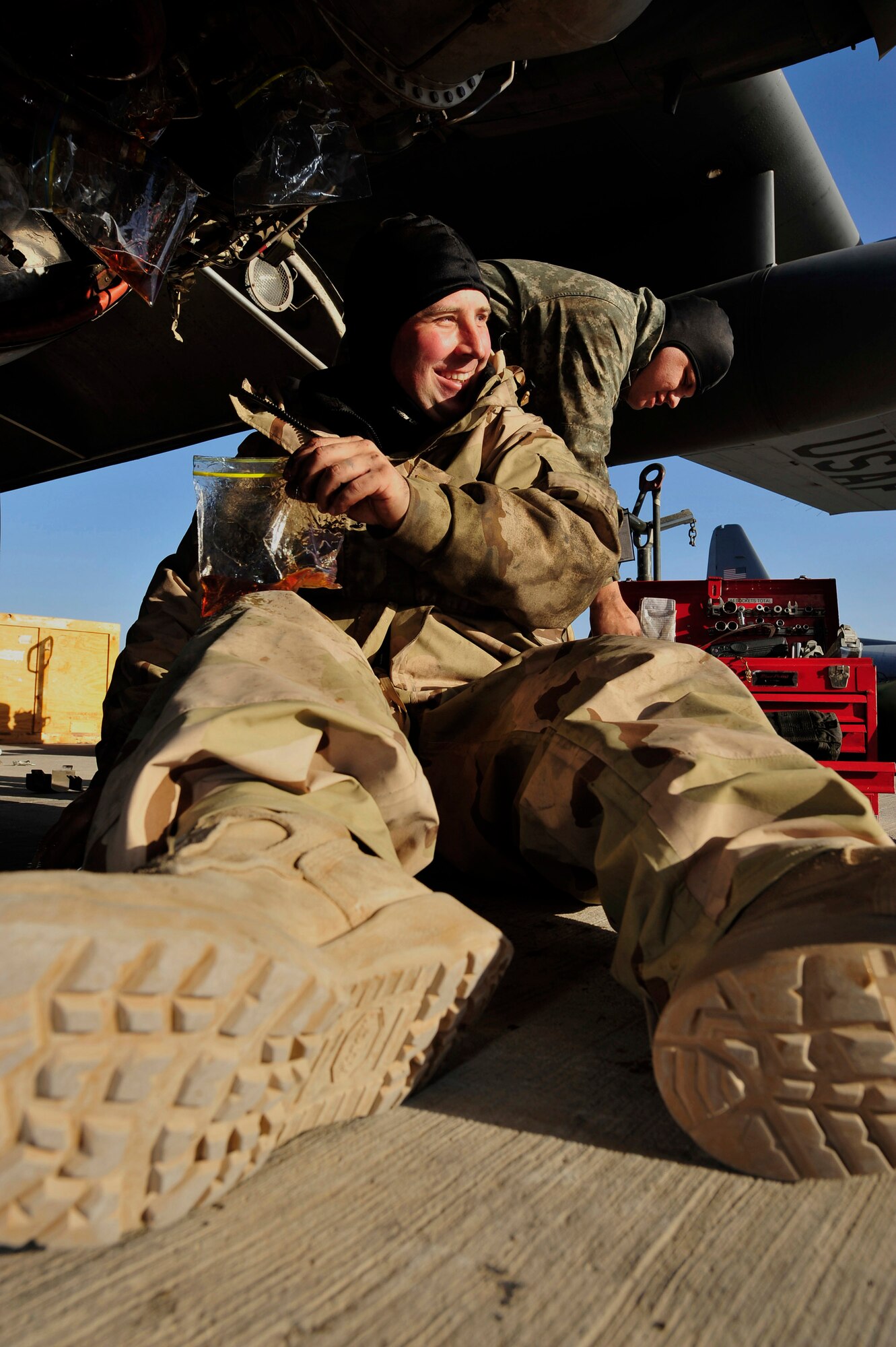 Technical Sgt. Sam Harmon takes a moment for a laugh as he caps the oil and fuel lines before changing the auxiliary power unit of a C-130 Hercules Jan. 16 at Joint Base Balad, Iraq. Sergeant Harmon is a 777th Expeditionary Aircraft Maintenance Unit jet engine mechanic deployed from Little Rock Air Force Base, Ark. He is a native of Santa Barbara, Calif. (U.S. Air Force photo/Senior Airman Elizabeth Rissmiller) 
