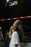 Tech. Sgt. Vanessa Sidney and her daughter, Anissa, look up at the Jumbotron to watch a surprise video message from husband and father, Tech. Sgt. Marcus Sidney, 12th Security Forces Squadron, who is currently deployed in support of Operations Iraqi and Enduring Freedom. Anissa served as the honorary ball girl for the Spurs basketball game during military appreciation night Jan. 23. (U.S. Air Force photo by Melissa Peterson)