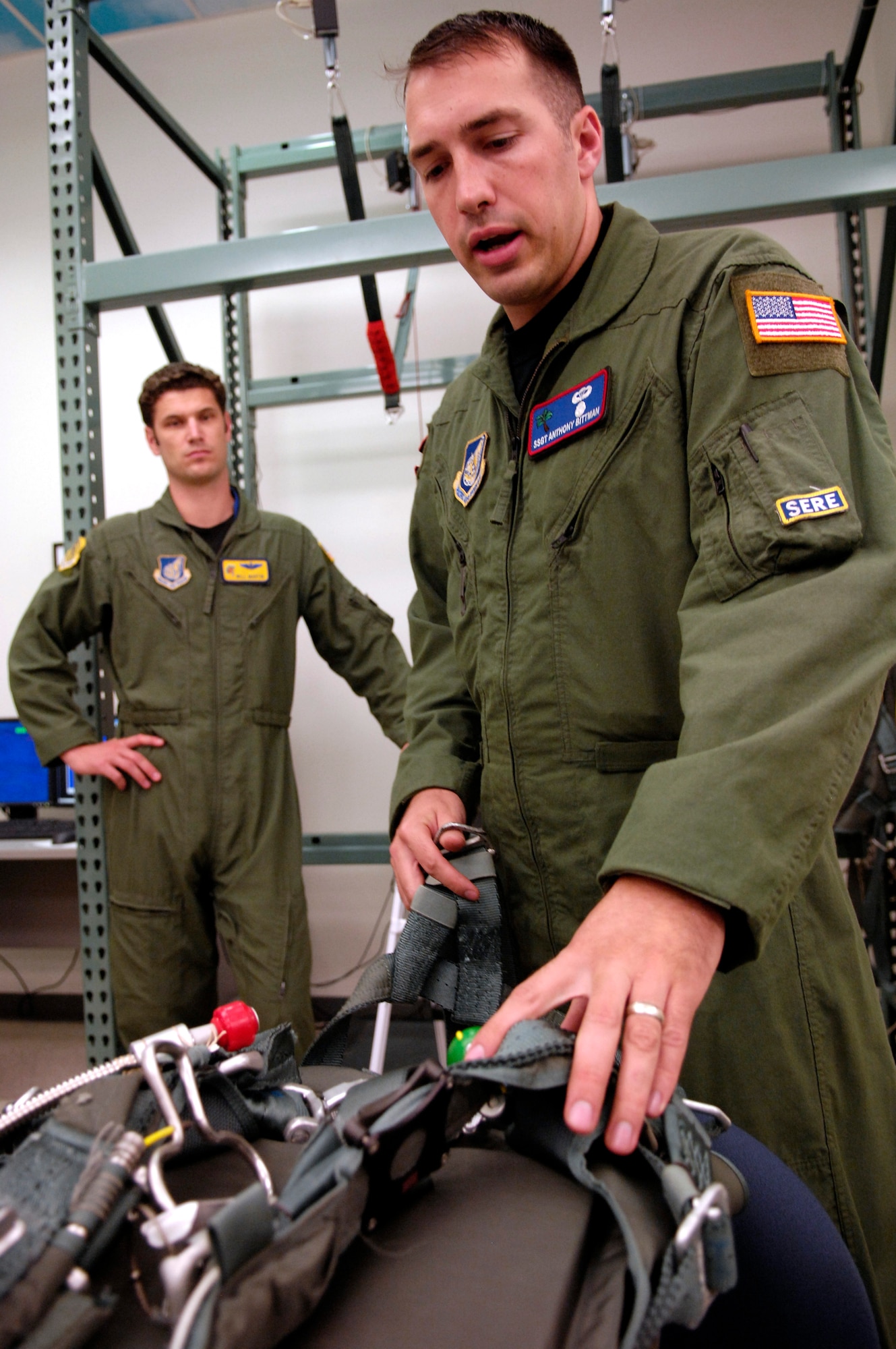 Maj. Will Martin (left), a pilot with the 535th Airlift Squadron at Hickam Air Force Base, Hawaii, listens as Staff Sgt. Anthony Bittman provides guidance for using the parachute simulator during a refresher parachute training class Jan 24.   Aircrews require annual non-ejection parachute training so they are current according to Air Force instructions. Sergeant Bittman is a survival, evasion, resistance, escape, or SERE, instructor with the 15th Airlift Wing at Hickam.  (U.S. Air Force photo/Tech. Sgt. Cohen A. Young)
