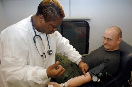 Tomeka Franklin locates Staff Sgt. Ray Green?s vein prior to drawing his blood during an American Red Cross blood drive held in the Home Station Check hangar Jan. 23. Thirty-four Team Charleston members participated in the blood drive to donate a total of thirty-eight pints of red cell blood and whole blood. Mrs. Franklin is a certified medical assistant with the ARC and Sergeant Green is assigned to the 437th Operations Support Squadron. (U.S. Air Force photo/Staff Sgt. Marie Cassetty)
