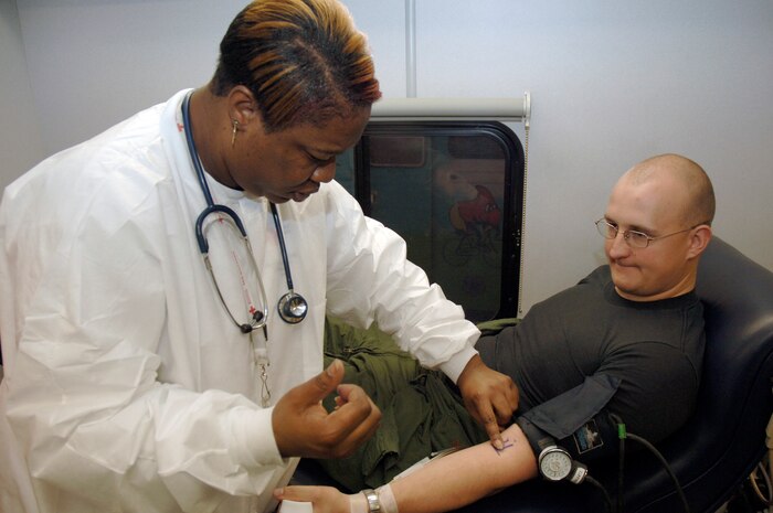 Tomeka Franklin locates Staff Sgt. Ray Green?s vein prior to drawing his blood during an American Red Cross blood drive held in the Home Station Check hangar Jan. 23. Thirty-four Team Charleston members participated in the blood drive to donate a total of thirty-eight pints of red cell blood and whole blood. Mrs. Franklin is a certified medical assistant with the ARC and Sergeant Green is assigned to the 437th Operations Support Squadron. (U.S. Air Force photo/Staff Sgt. Marie Cassetty)