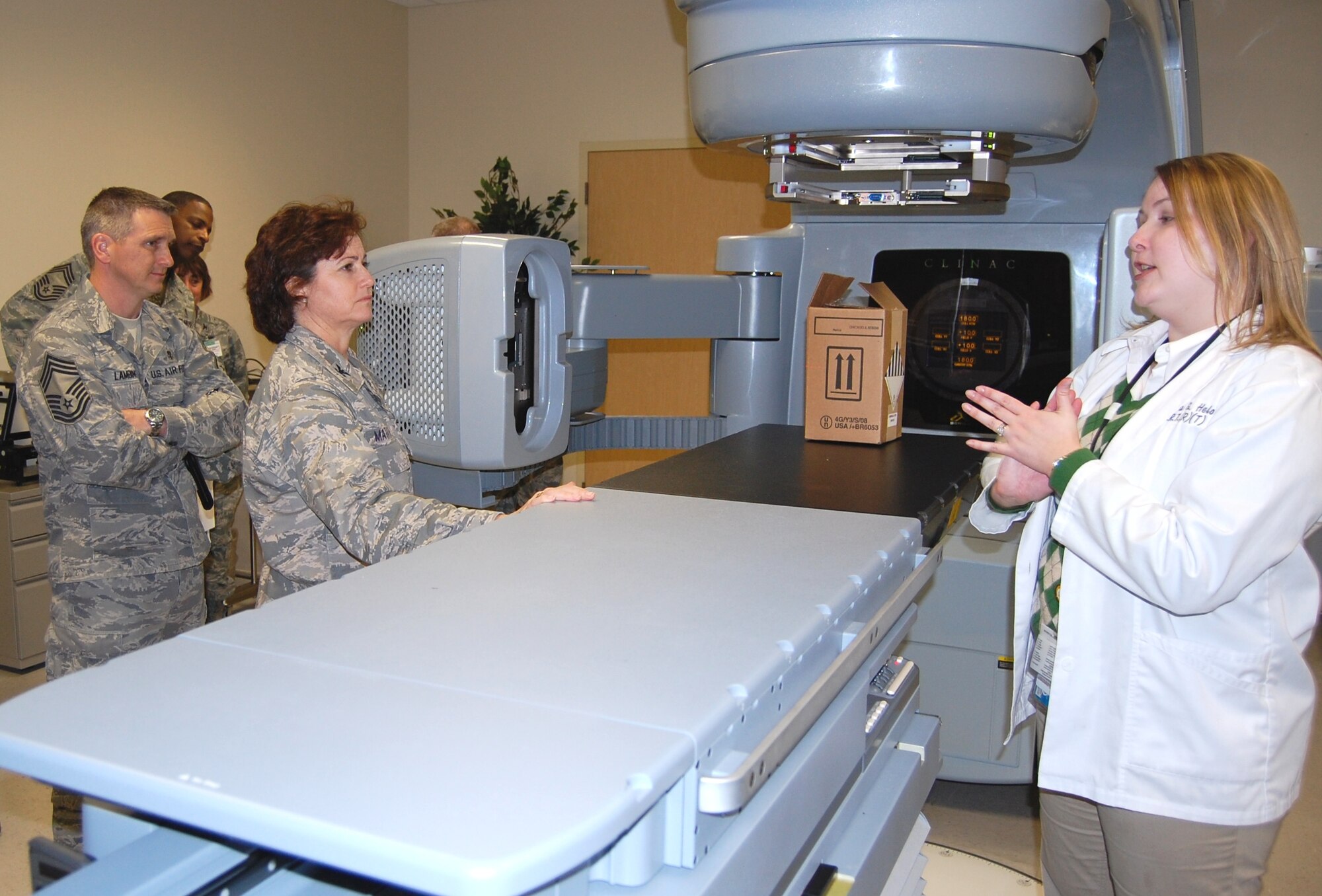 From left, Chief Master Sgt. Kevin Lambing, chief of the enlisted medical force at Air Education and Training Command, and Col. (Dr.) Margaret Matarese, AETC’s surgeon general, listen as Kendra Helo demonstrates how the radiation oncology department’s 2100IX linear accelerator operates, Jan. 21.  Ms. Helo, chief radiation therapist with the 81st Medical Operations Squadron, used a box to simulate a patient.  Colonel Matarese was making her first visit to Keesler Medical Center since assuming her post.  For Chief Lambing, it was a “homecoming” of sorts — he’d been assigned to the medical center from 1989-1999.  (U.S. Air Force photo by Steve Pivnick)

