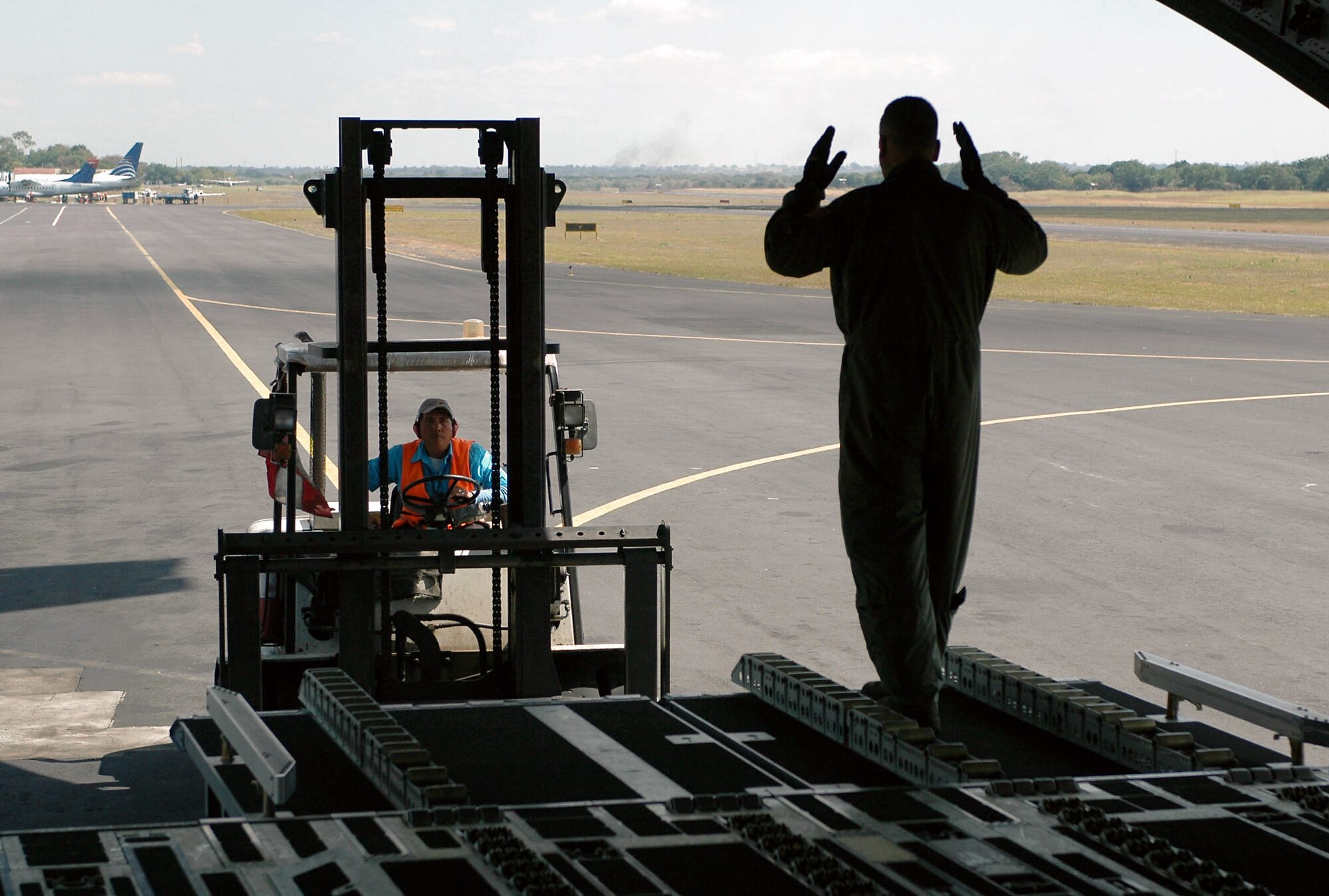 Master Sgt. Mike Wright aligns the forklift driver to unload cargo from a C-17 Globemaster III Jan. 18 at the Managua International Airport, Nicarauga. Approximately 18,000 pounds of cargo consisting of desks, chairs, file cabinets and books were delivered for use at a Nicaraugan university library. Sergeant Wright is a loadmaster with the Air Force Reserve's 326th Airlift Squadron at Dover Air Force Base, Del. (U.S. Air Force photo/Capt. Marnee A.C. Losurdo)