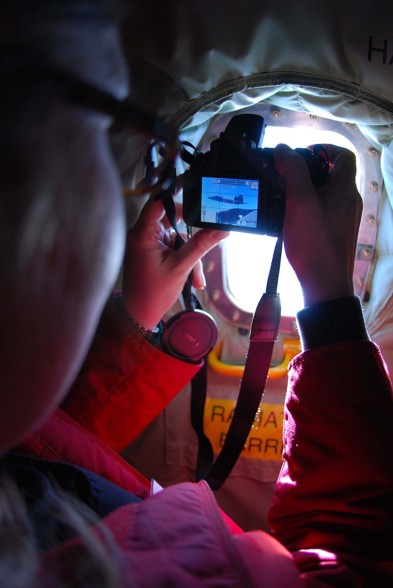Dr. Paula Rose, Allen Family Foods health service director, takes a photo of an F-16 through a porthole window on the aircraft. The group of volunteers and employers were able to roam around the KC-135 in flight asking questions and observing the flight crew.