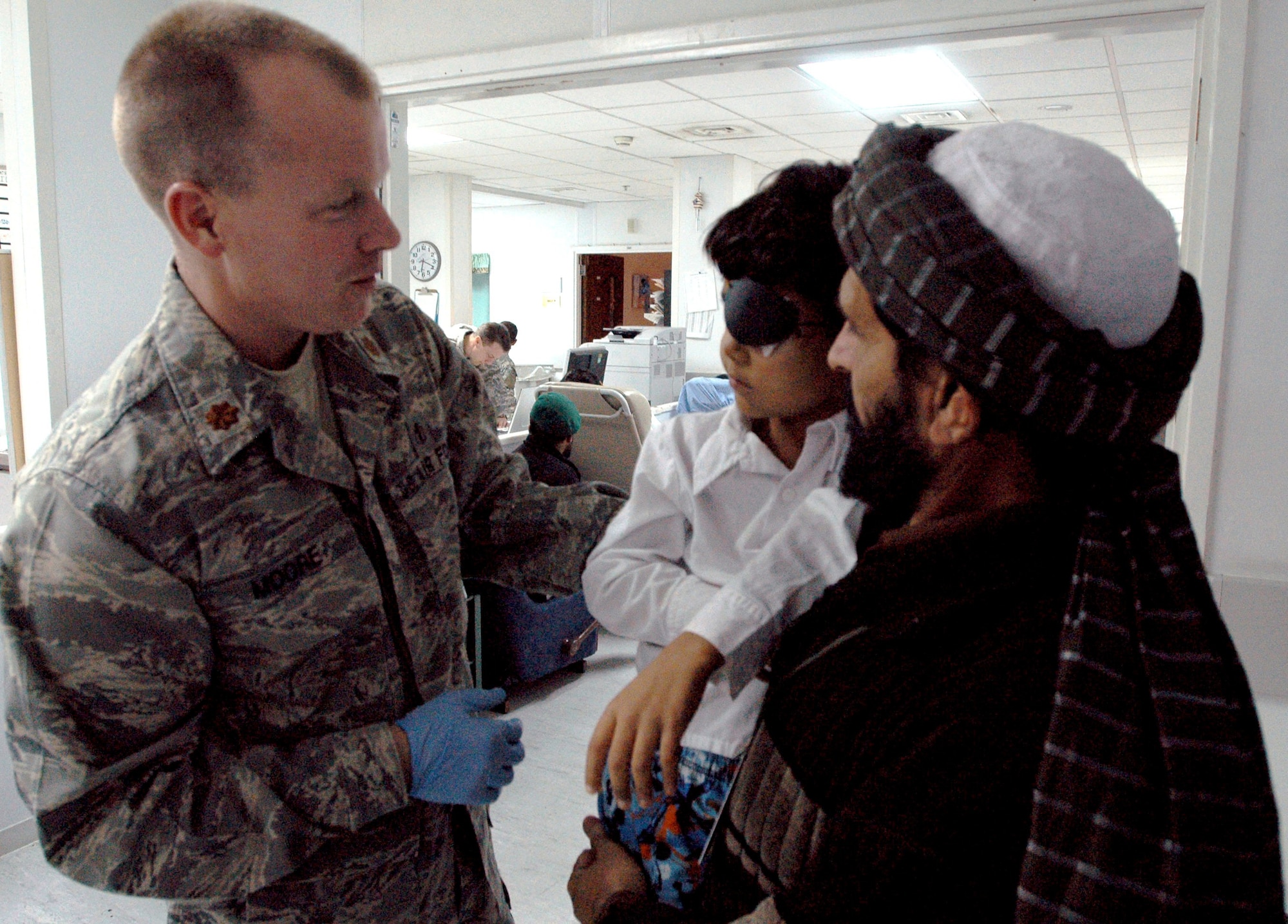 Dr. (Maj.) Brian Moore, a head and neck surgical oncologist, talks to Shair Ahmad and his son, Hamid, after Hamid's surgery to remove a tumor in his eye.  Doctor Moore is deployed from Eglin AFB's 96th Medical Group. (USA photo/SPC Anna Perry) 