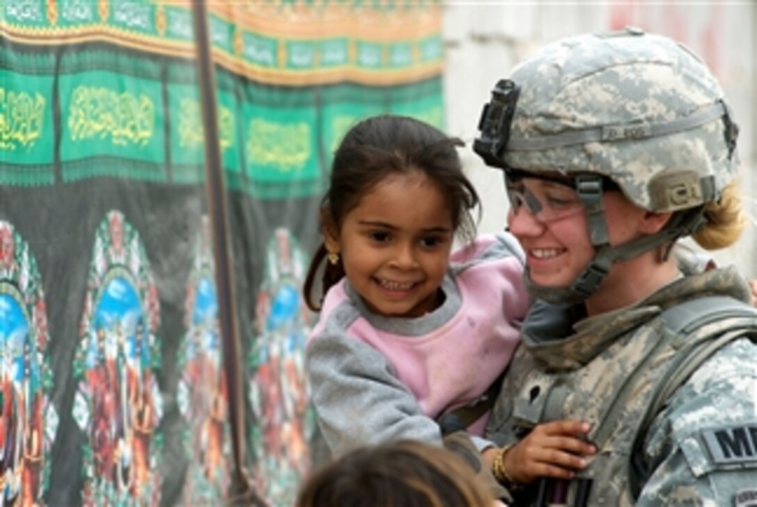U.S. Army Spc. Melissa McIntyre of the 793rd Military Police Battalion, 8th Military Police Brigade holds a child while on patrol in the Hayyaniyah district of Basra, Iraq, on Jan. 20, 2009.  Her unit teamed with Iraqi police to deliver medical supplies to a local hospital.  
