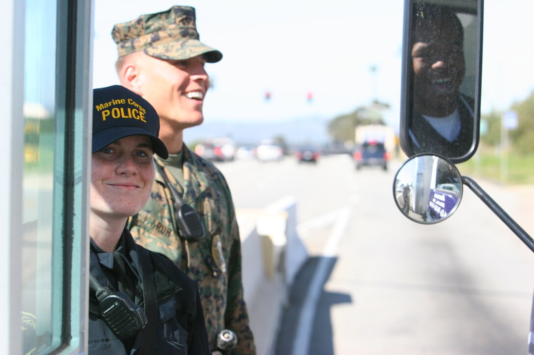 Lance Cpl. Jack L. Ruh (right), military police, Security Battalion, Marine Corps Base Camp Pendleton, works alongside recently hired Ashley C. Toro (left), civilian police officer, MCB, as they monitor traffic going in and out Pendleton’s front gate.