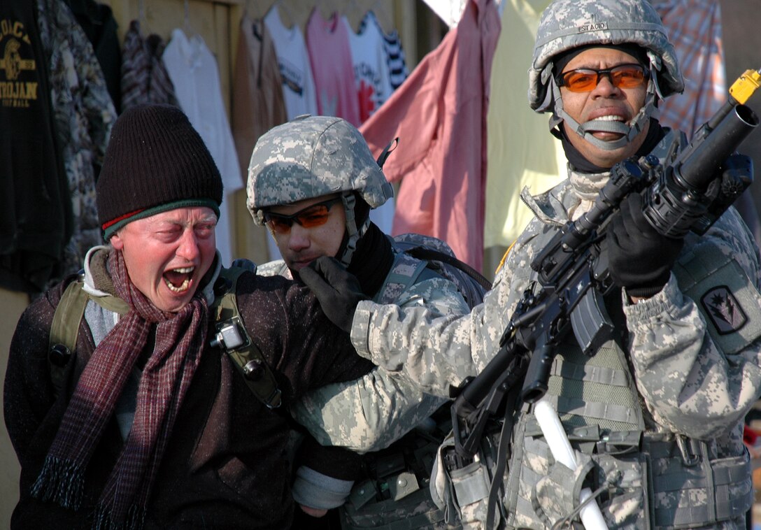 Soldiers from the California National Guard apprehend a simulated high value target during a non-lethal weapons scenario training session. The training facilities combined with the actors known as civilians on the battlefield or COBs make for a realistic training environment for service members rotating through the Joint Multinational Readiness Center here. Marine non-lethal weapons instructors Marine Forces Europe traveled here to conduct the training for the soldiers as part of the soldier?s predeployment training in preparation for an upcoming rotation with the NATO-led Kosovo Force.